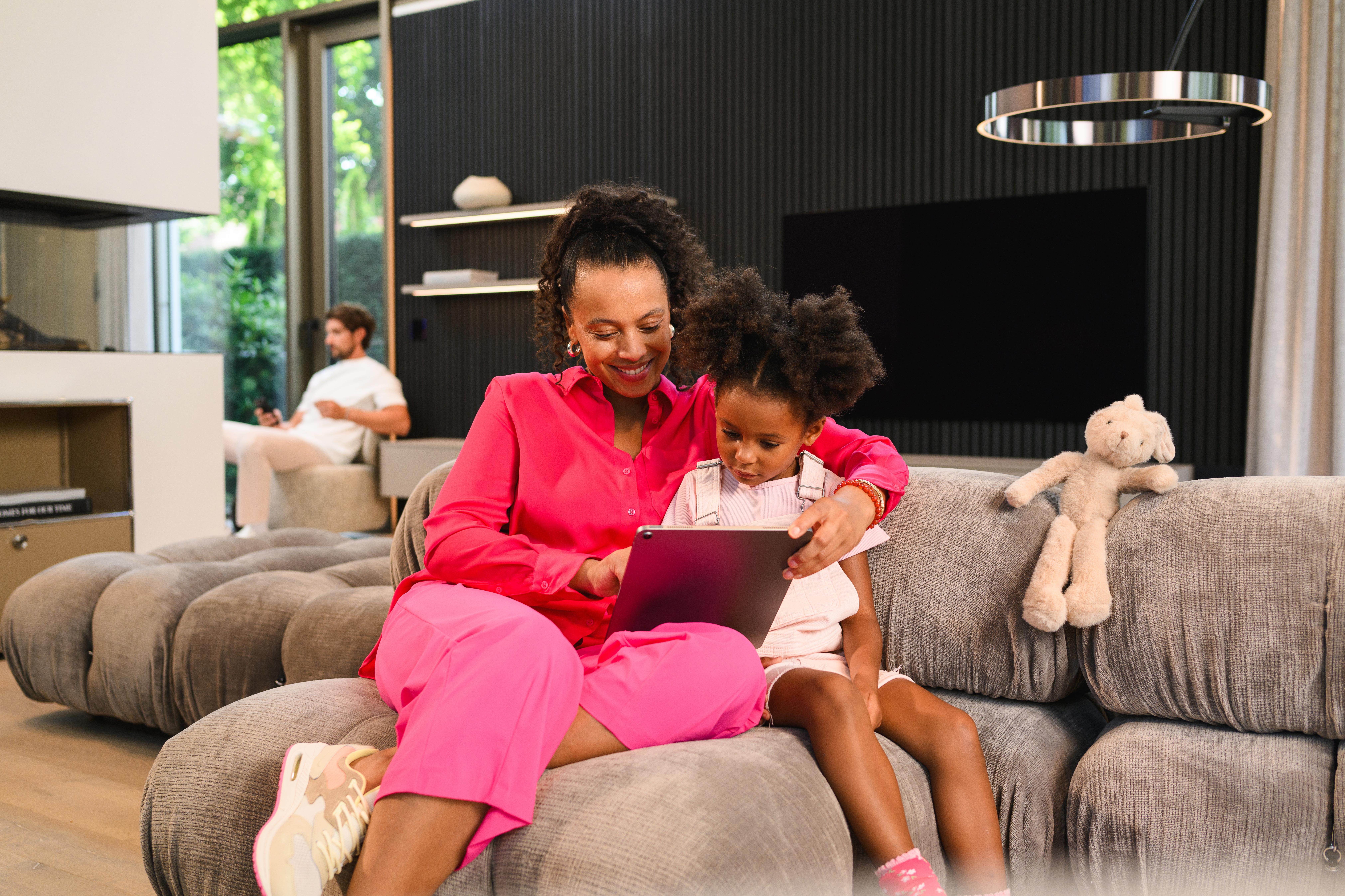 Portal Mercedes-Benz Finance Kobieta z córką na kanapie przeglądają dokumenty na laptopie.