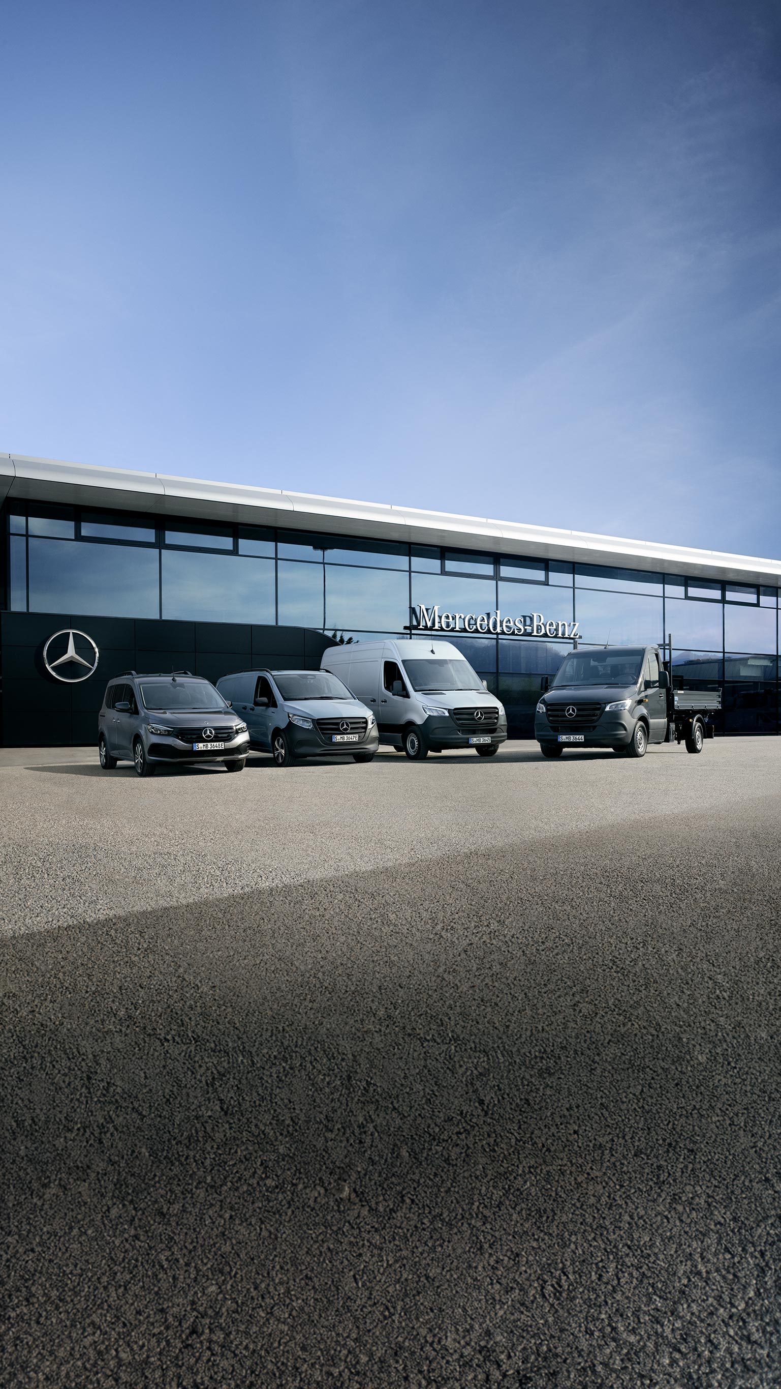 Cztery samochody dostawcze Mercedes-Benz przed budynkiem z logo Mercedes-Benz na szklanej elewacji.