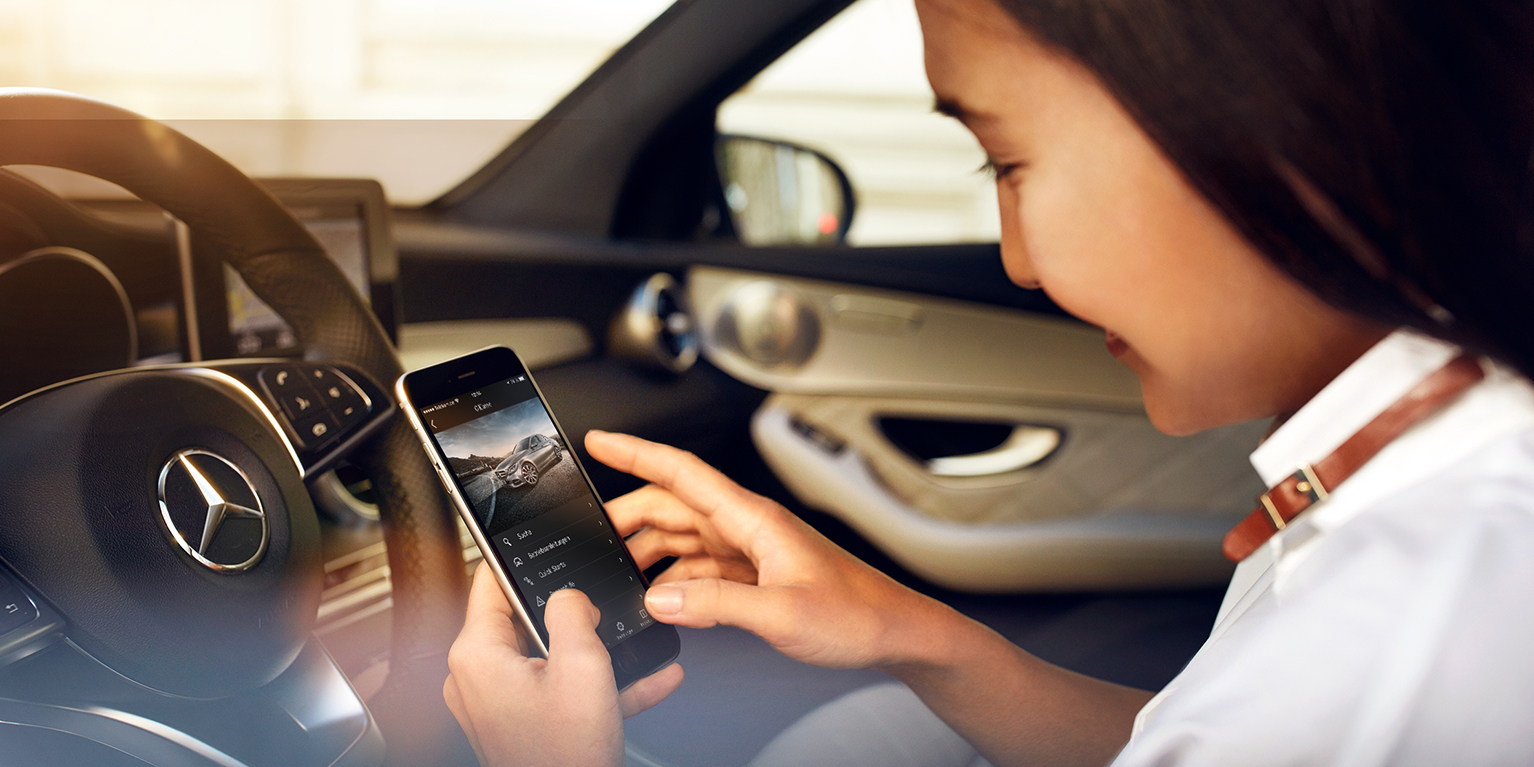 Instrukcje eksploatacji online | Mercedes-Benz Kobieta korzysta z cyfrowej instrukcje obsługi na swoim smartfonie.