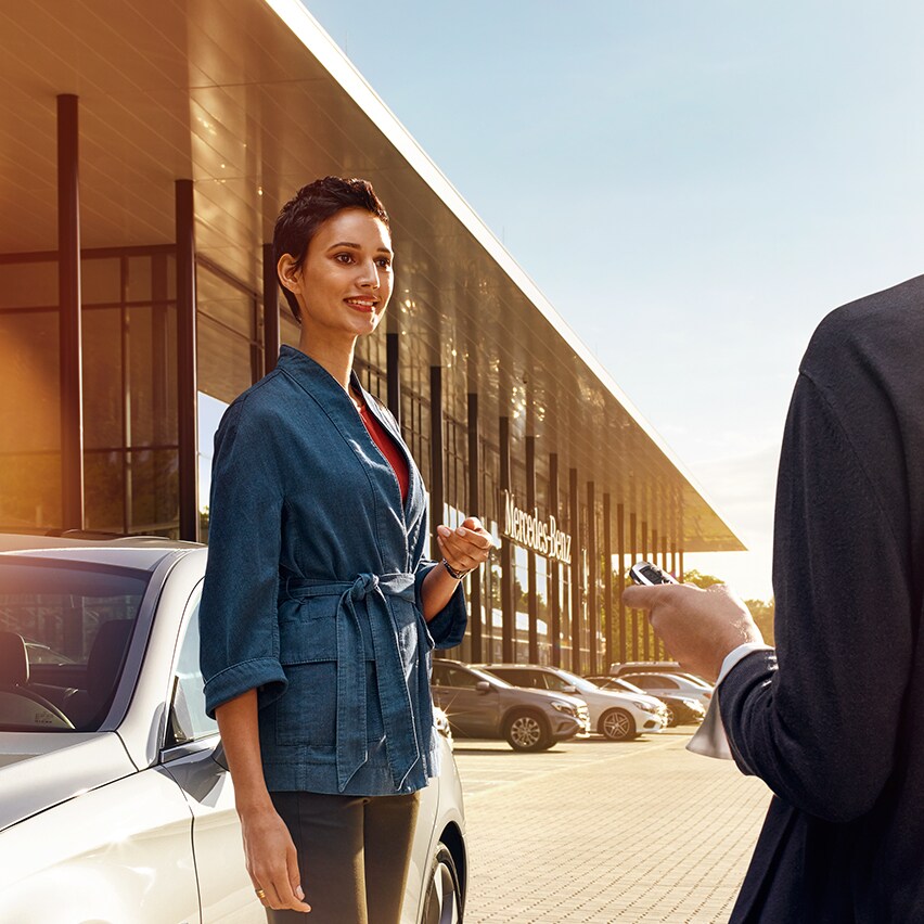 Doradca handlowy Mercedes-Benz przekazuje klientowi kluczyki do nowego Mercedesa.