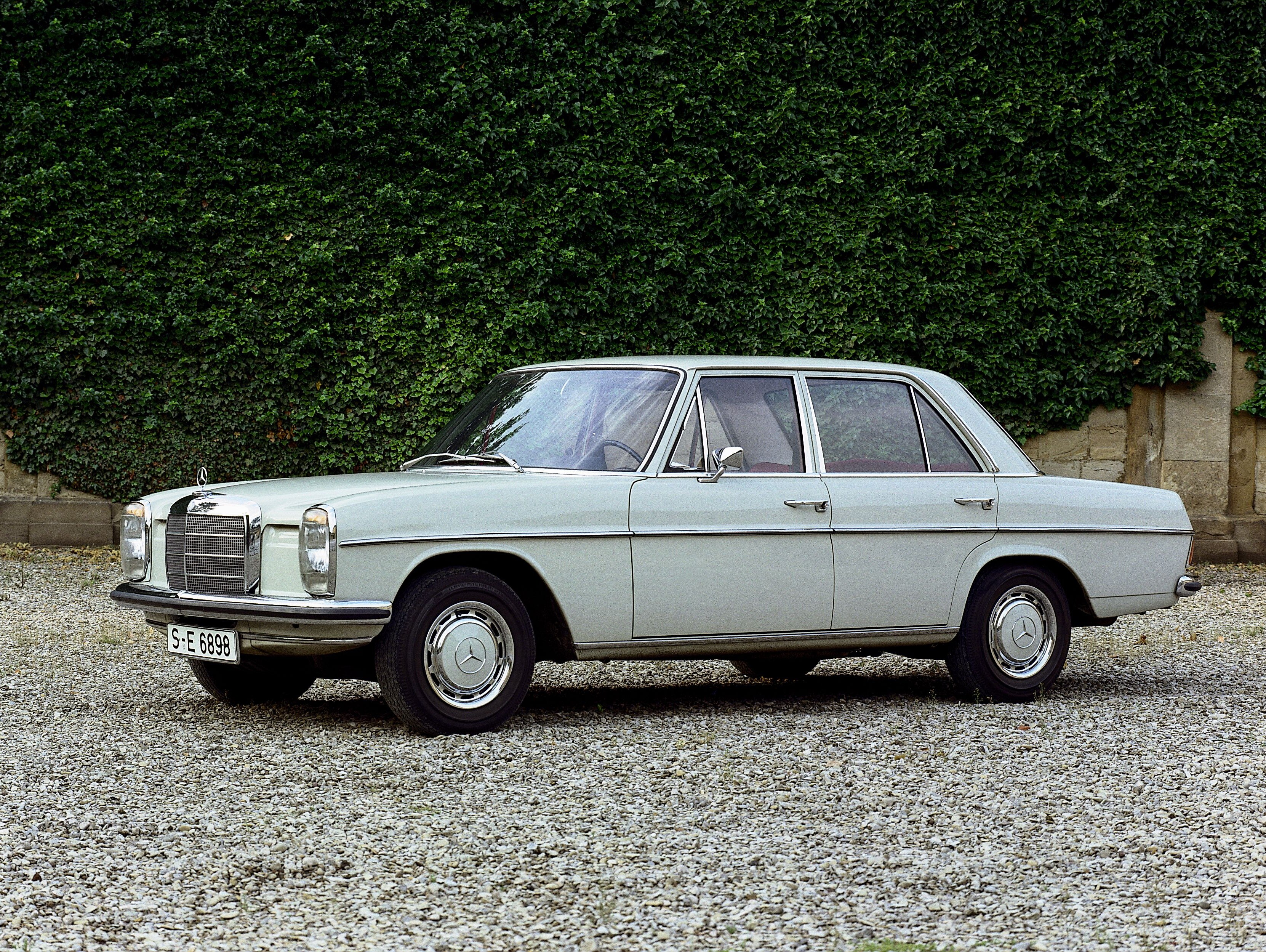 Mercedes-Benz 200, W 115 „Strich-Acht” na żwirowym parkingu.