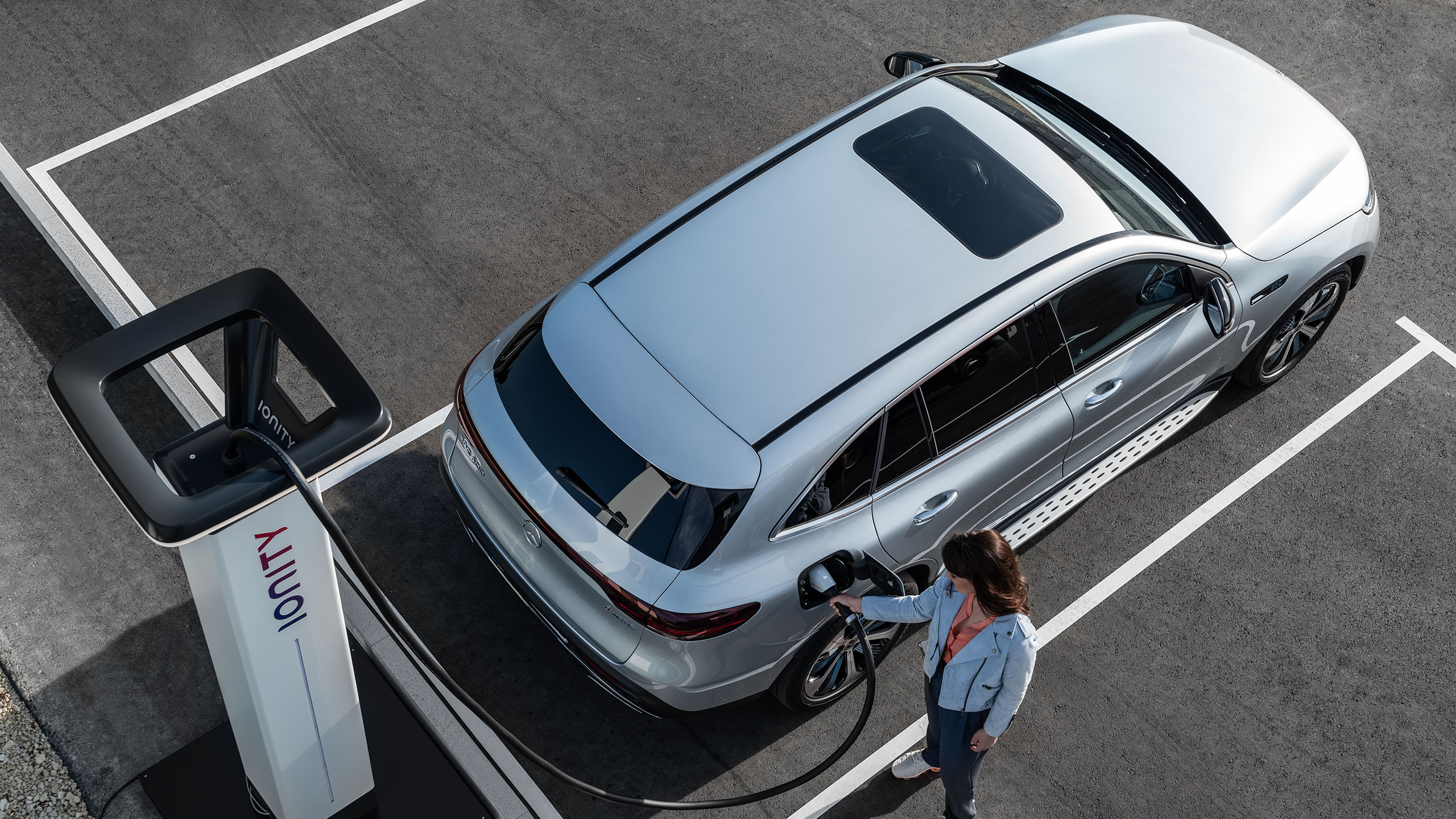 Ładowanie Kobieta podłącza swojego Mercedesa do stacji ładowania.