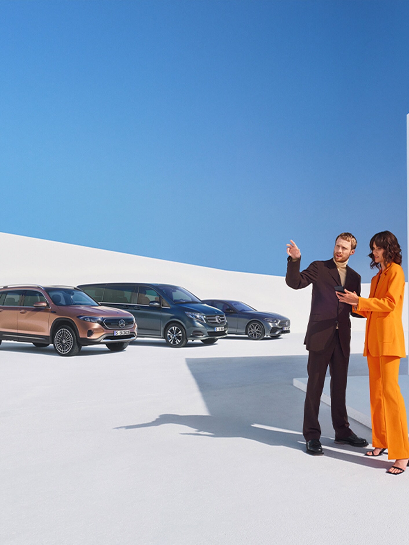 Mężczyzna i&nbsp;kobieta przed kilkoma pojazdami Mercedes-Benz.