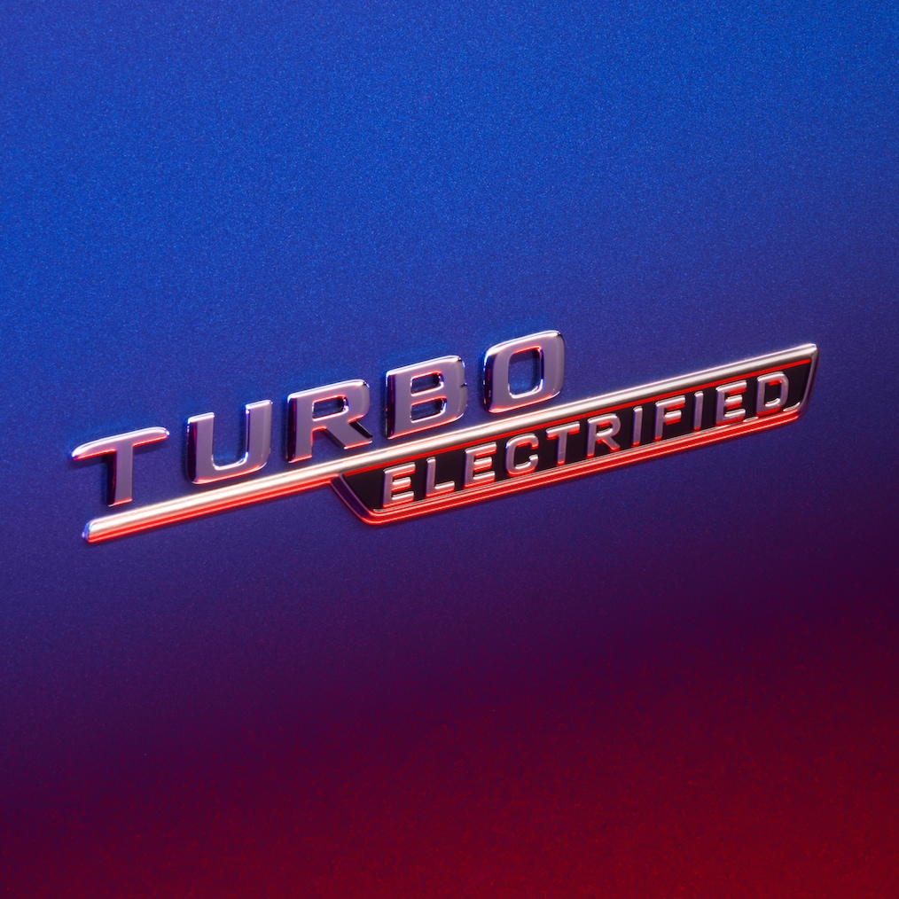 Emblemat TURBO E PERFORMANCE na przednim błotniku, podświetlony czerwonym światłem.