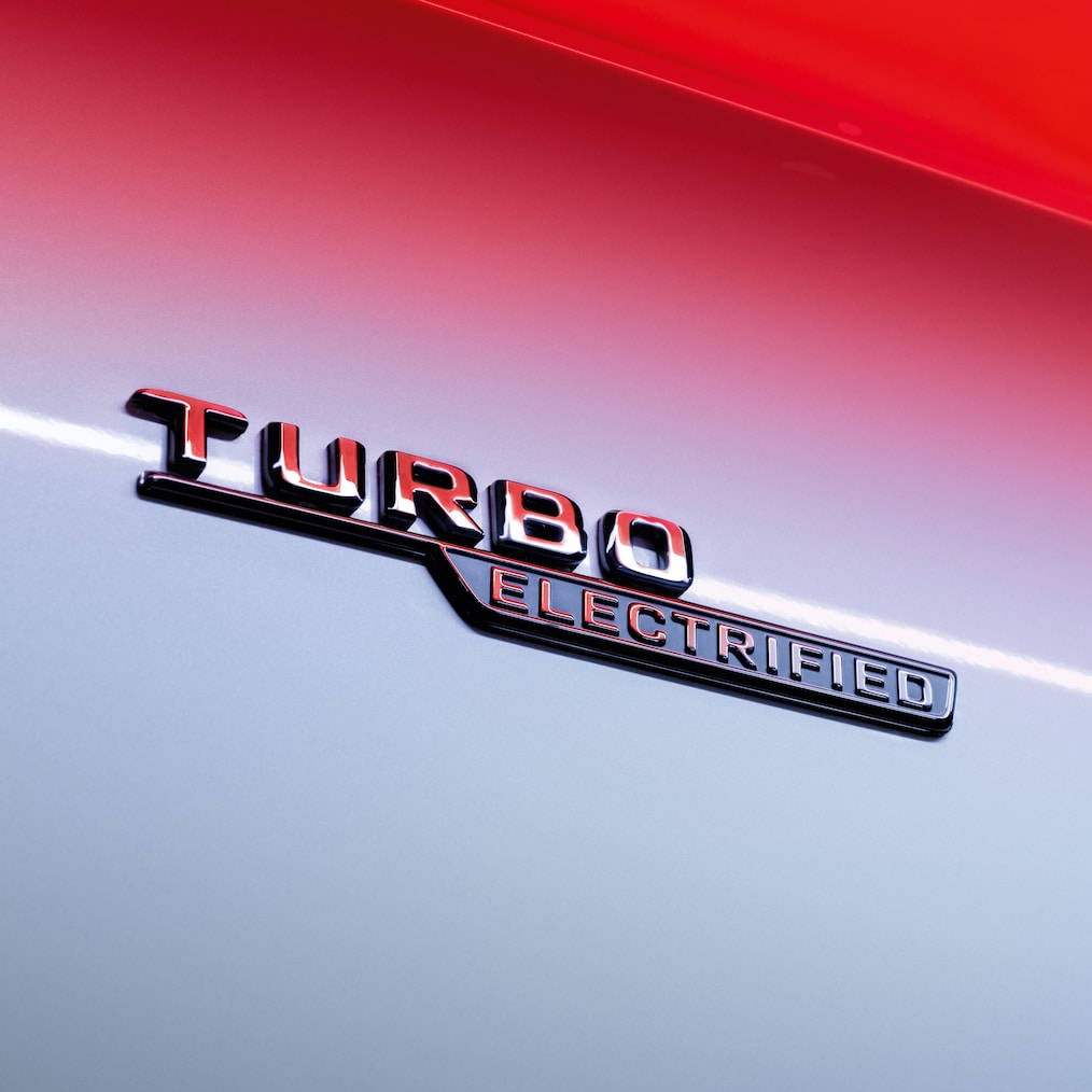 Zbliżenie na emblemat TURBO ELECTRIFIED na przednich błotnikach.