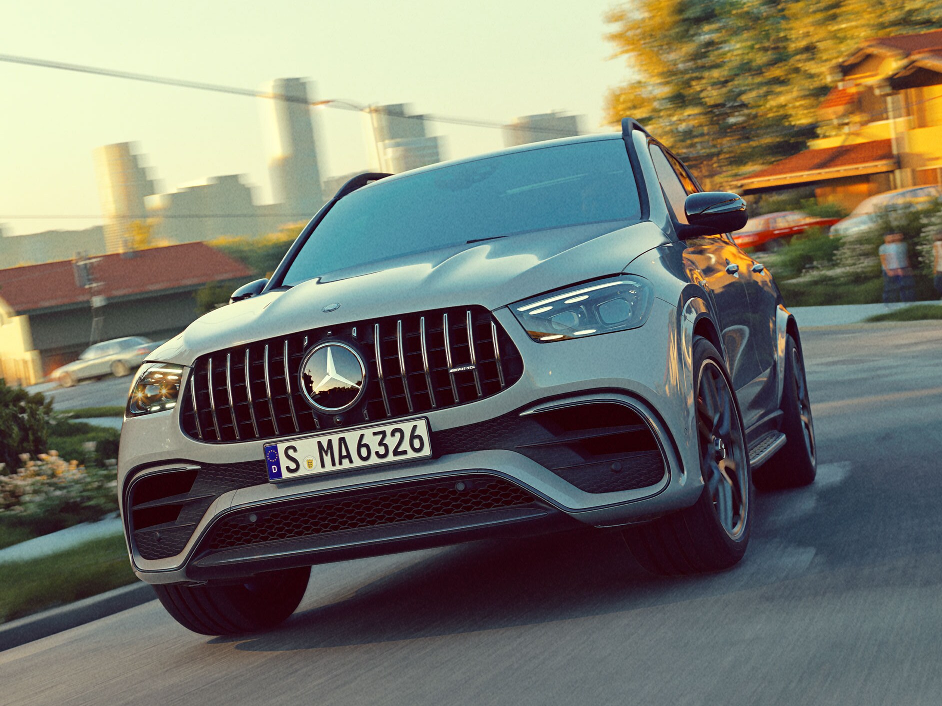 Model GLE SUV marki Mercedes-AMG w&nbsp;widoku z&nbsp;przodu jadący drogą z panoramą miasta w tle.