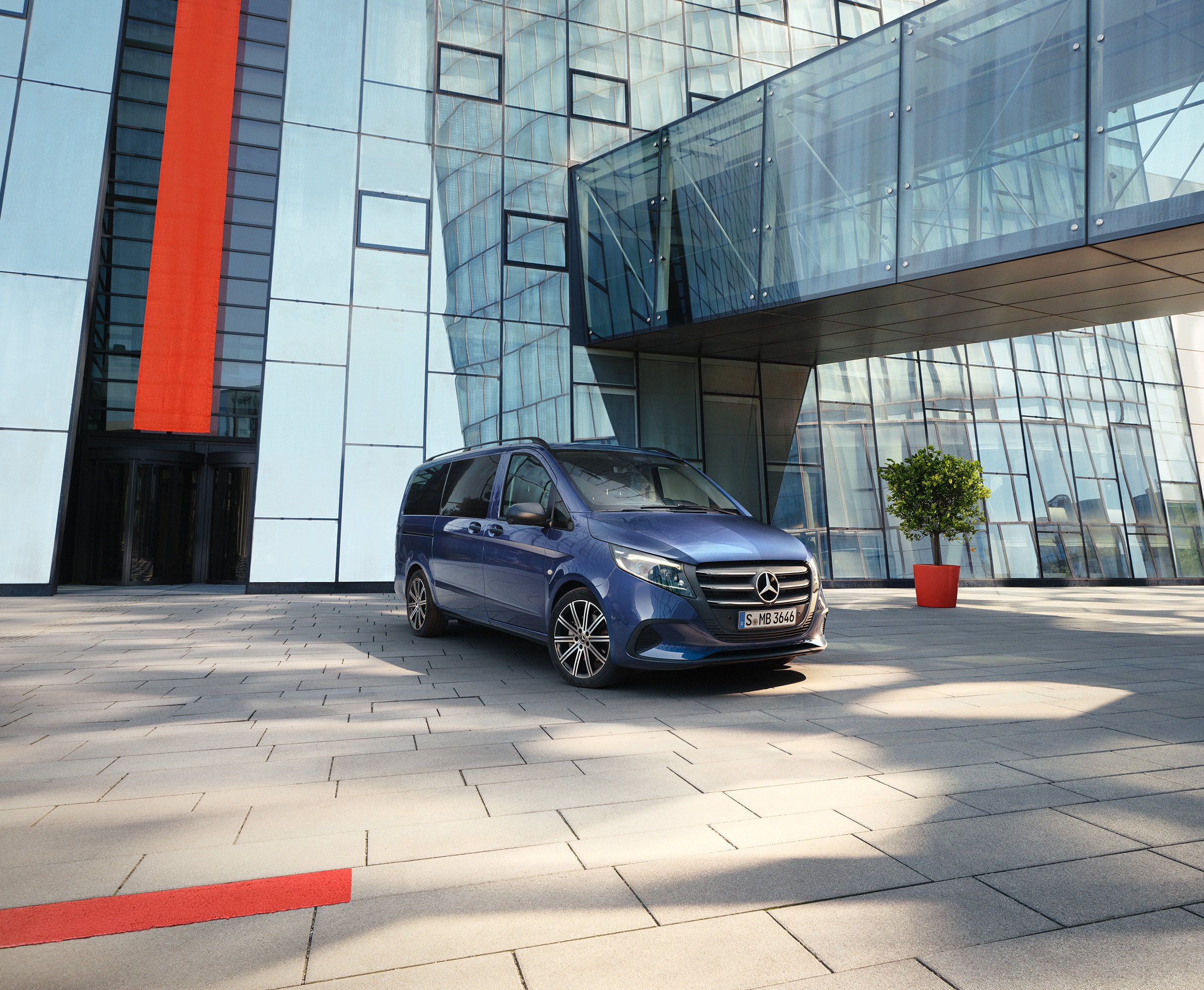 Vito Tourer | Modele vanów i samochodów kempingowych | Vany Mercedes-Benz Mercedes-Benz Vito Tourer z przesuwanymi drzwiami przed nowoczesnym budynkiem.