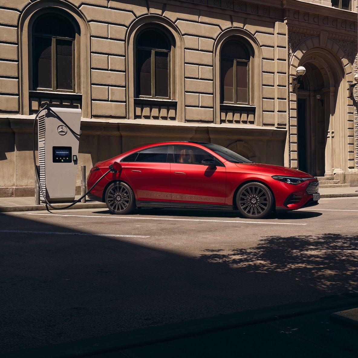 Widok z boku samochodu Mercedes-Benz CLA C174 stojącego przy stacji ładowania.