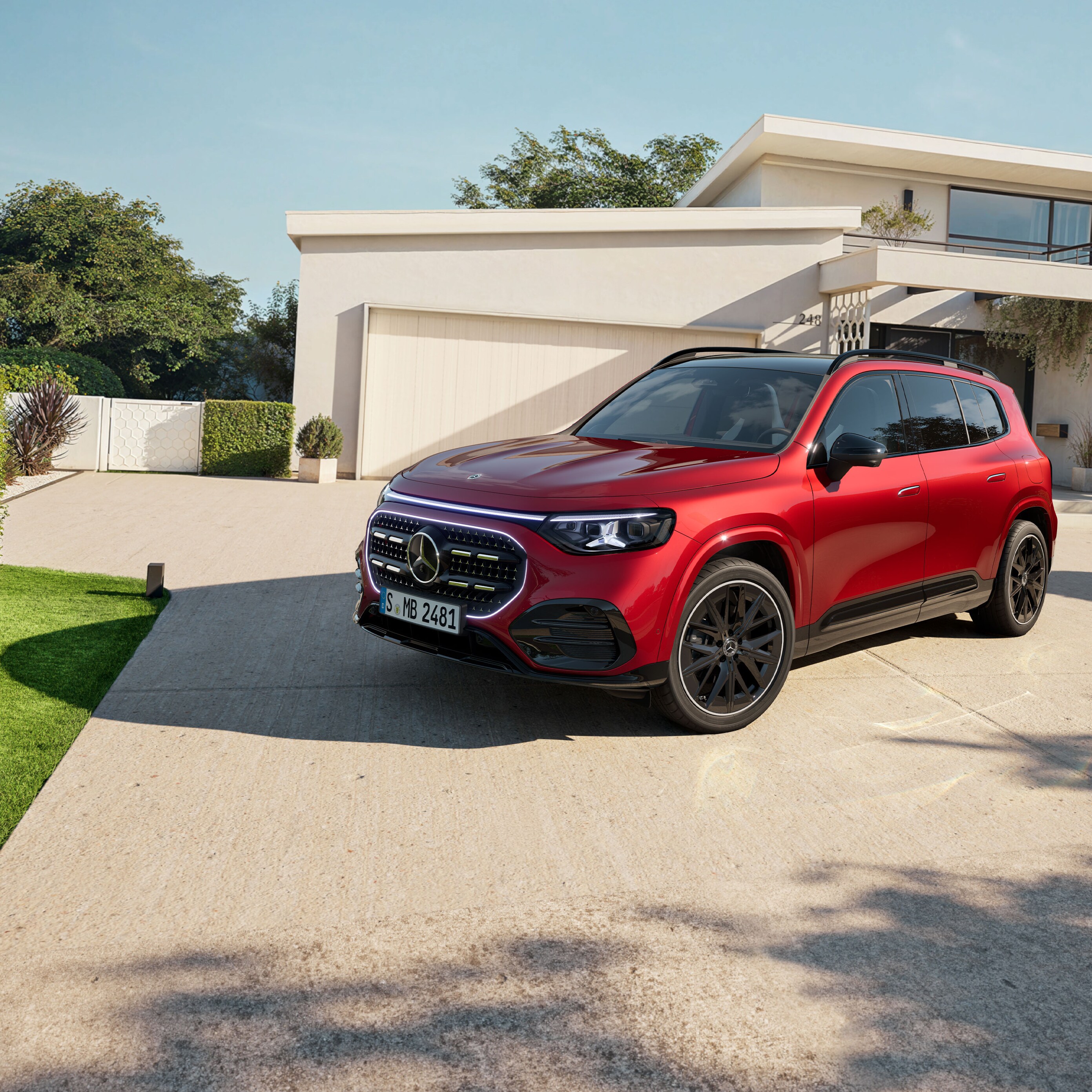 Czerwony Mercedes-Benz GLB SUV zaparkowany przed domem.