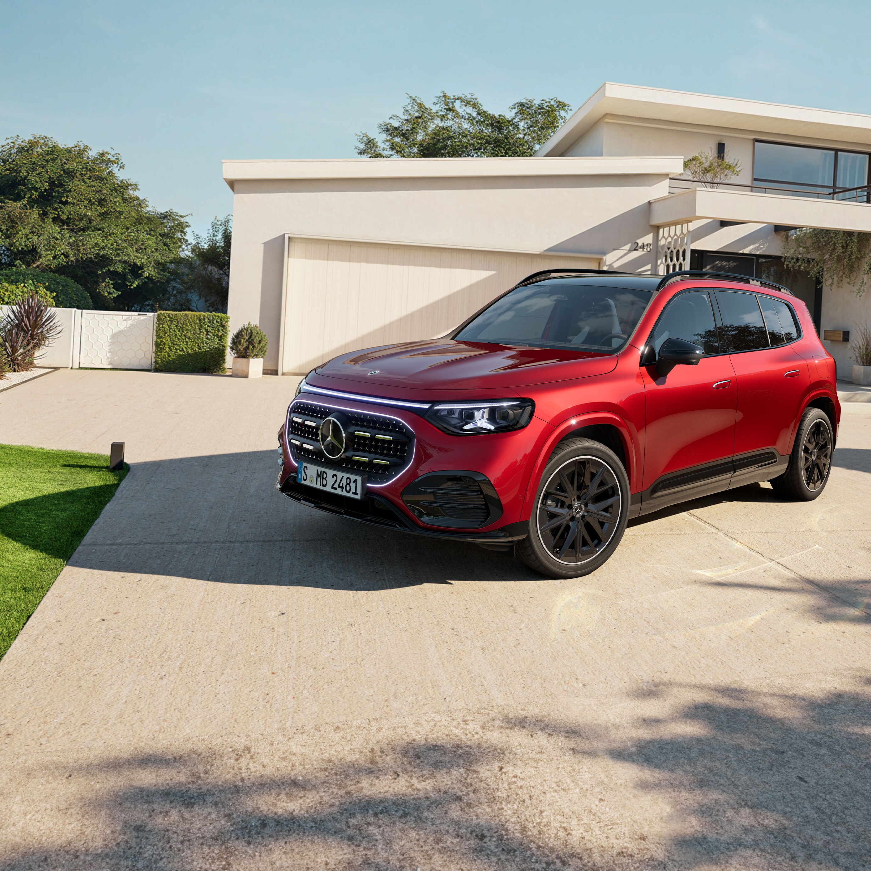 Czerwony Mercedes-Benz GLB SUV zaparkowany przed domem.