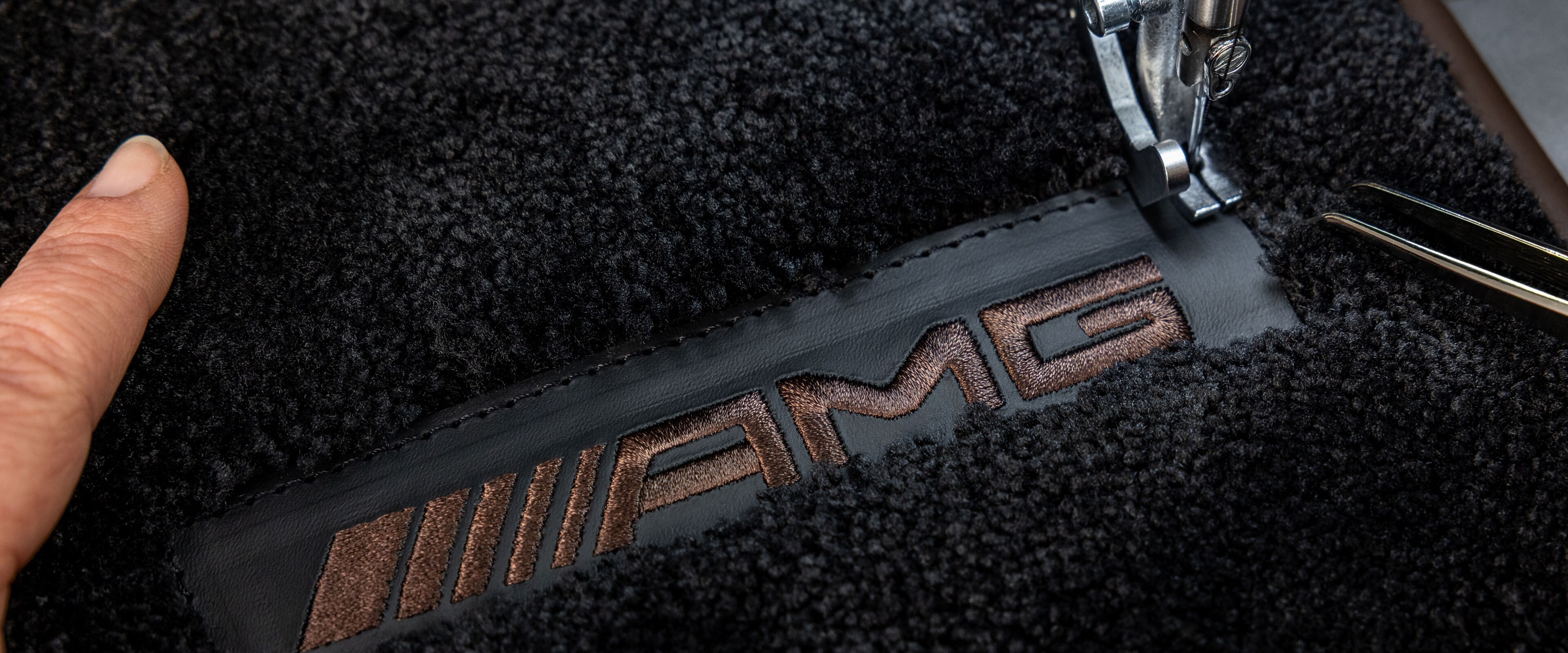 Emblemat MANUFAKTUR na ciemnej powierzchni w samochodzie Mercedes-AMG.