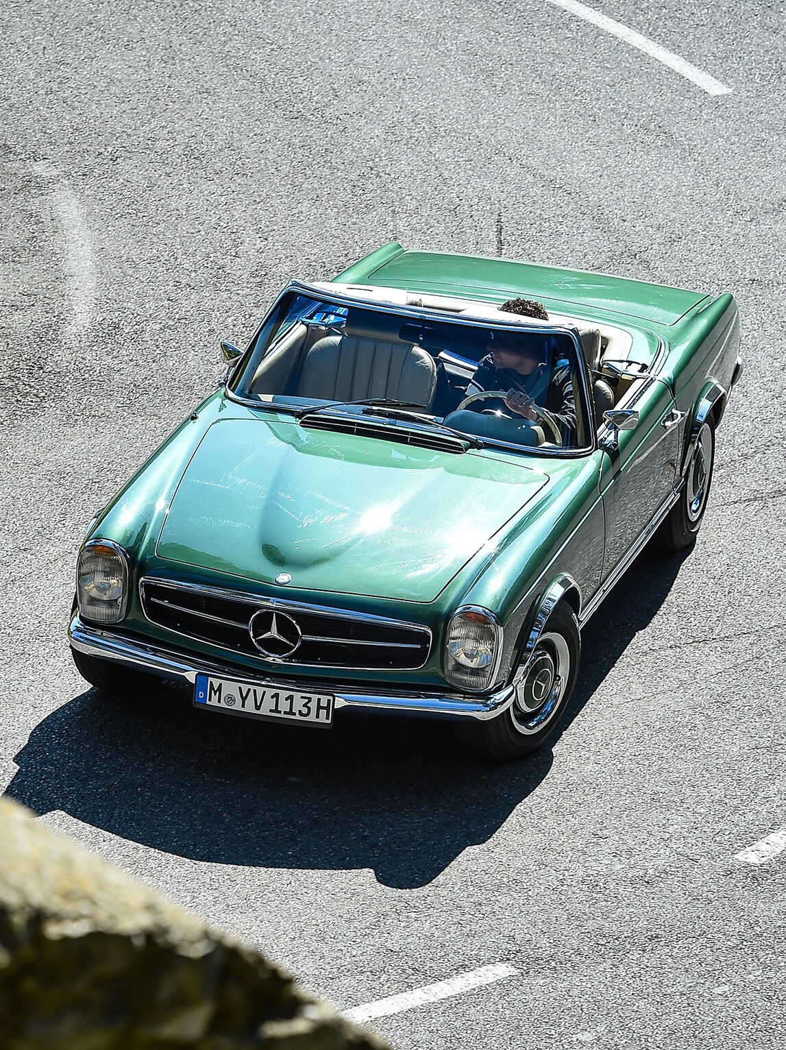 Zielony Mercedes SL na krętej, górskiej drodze.