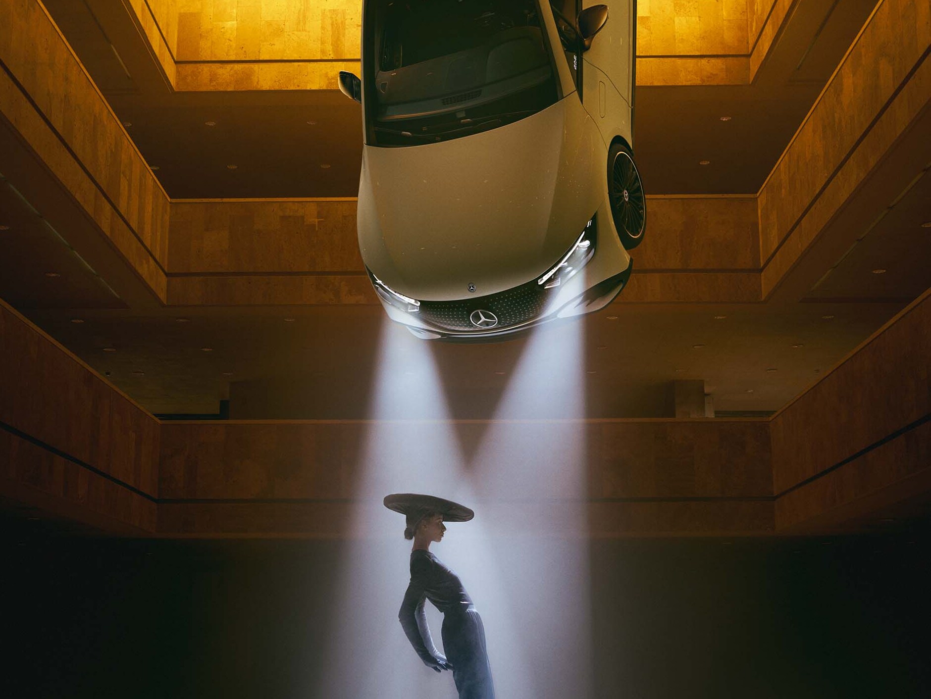 Ciemne pomieszczenie z wiszącymi pod sufitem reflektorami i kobietą stojącą w promieniu ich światła.