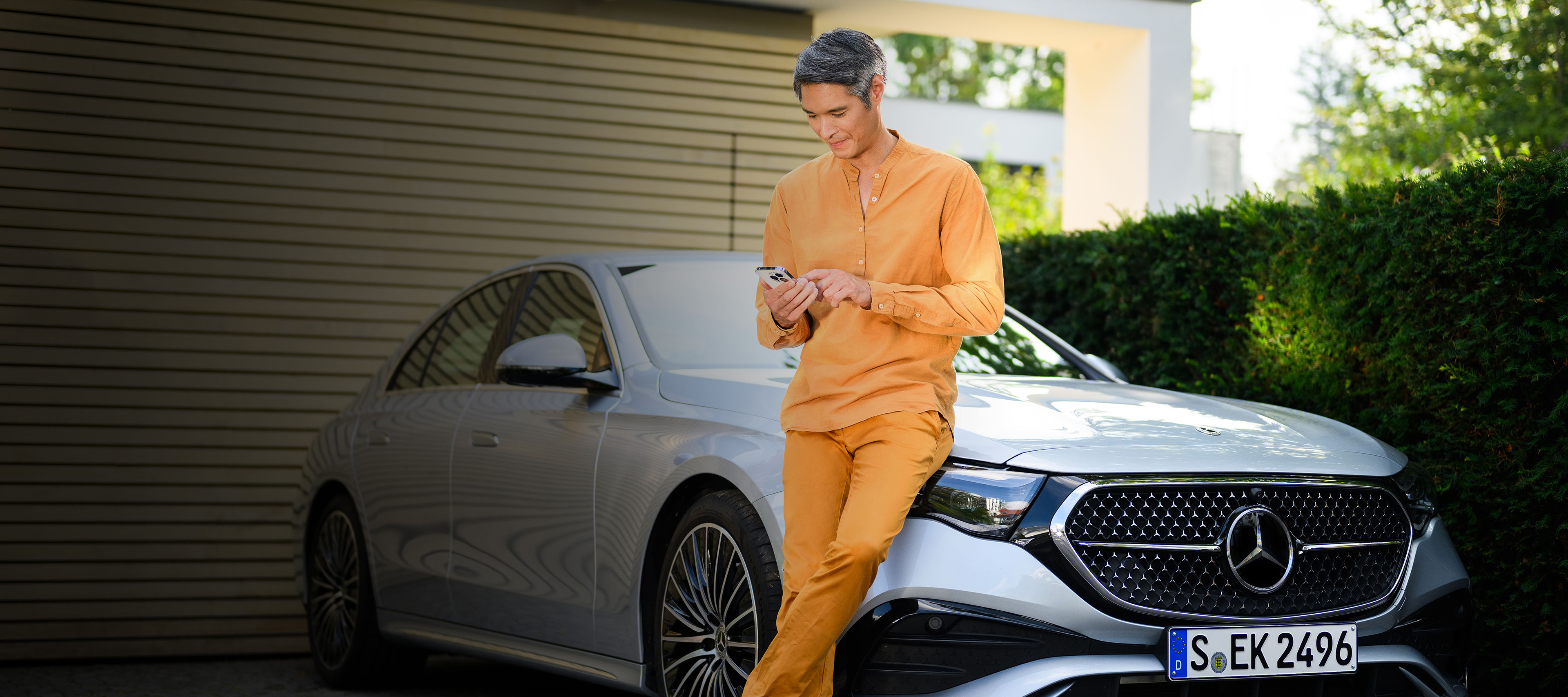 Oferty finansowania dla Twojego Mercedesa Mężczyzna opierająca się o srebrnego Mercedesa Klasy E.