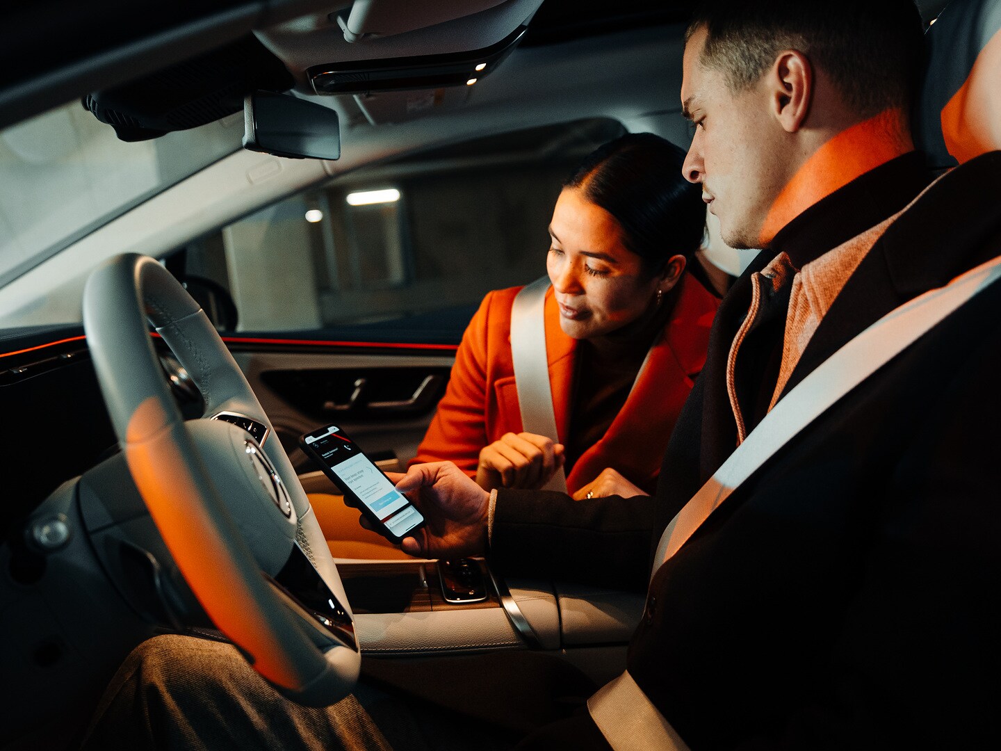 Para siedząca w Mercedesie patrzy razem na smartfon.