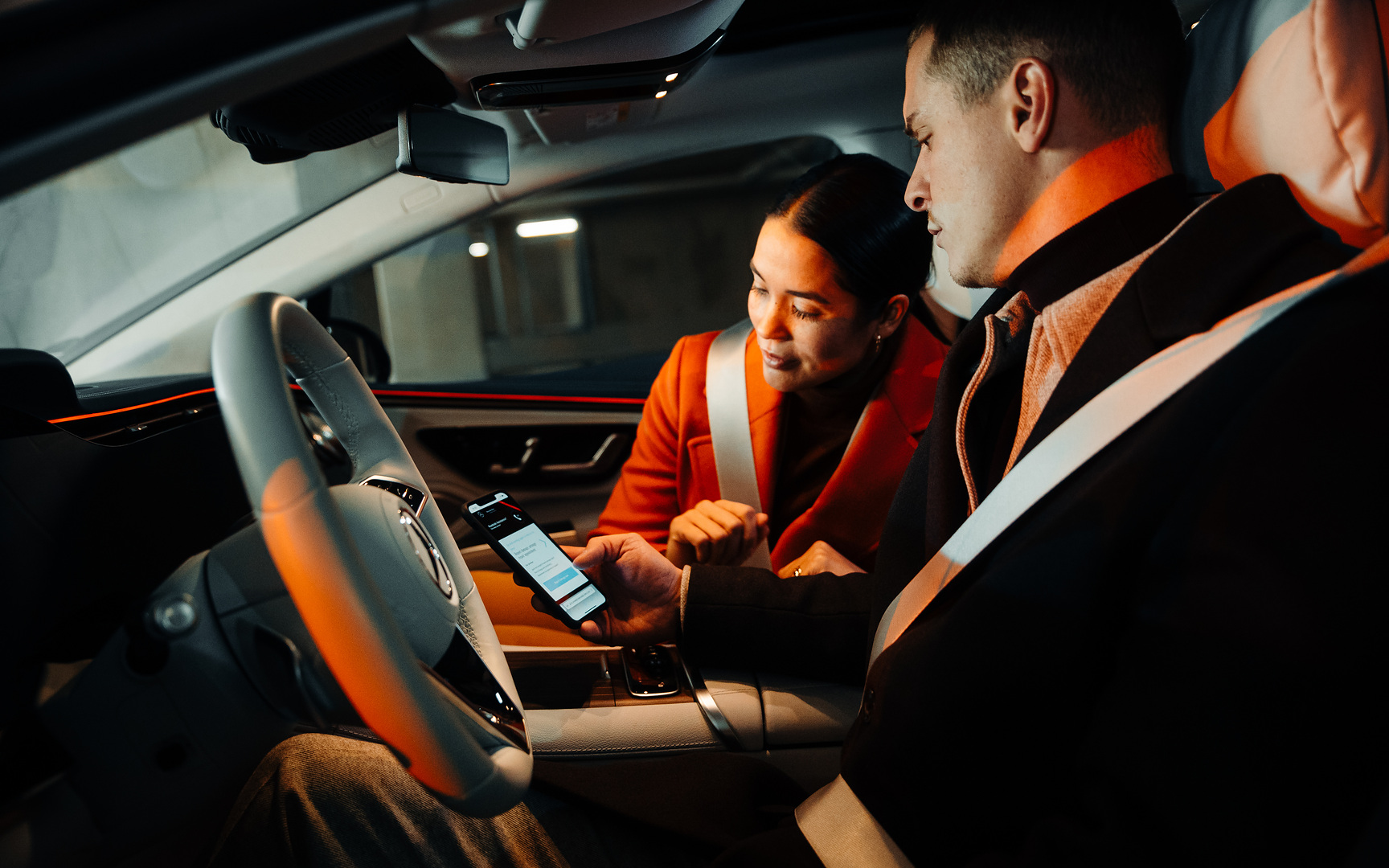 Zgłoś szkodę online | Mercedes-Benz Para siedząca w Mercedesie patrzy razem na smartfon.