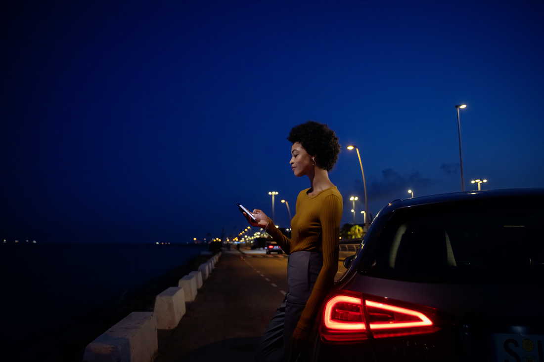 Kobieta oparta o Mercedesa Klasy A korzysta ze swojego smartfona. Instrukcje obsługi online | Mercedes-Benz