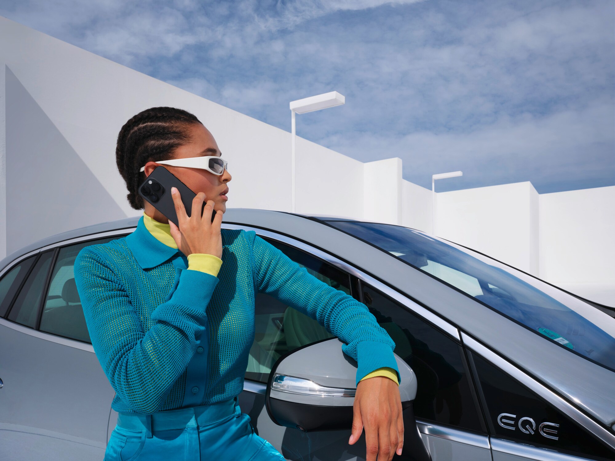 Osoba opierająca się o samochód Mercedes-Benz z telefonem w ręce.