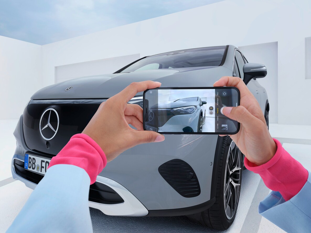 Kierowca wykonuje smartfonem zdjęcie swojego Mercedesa. 