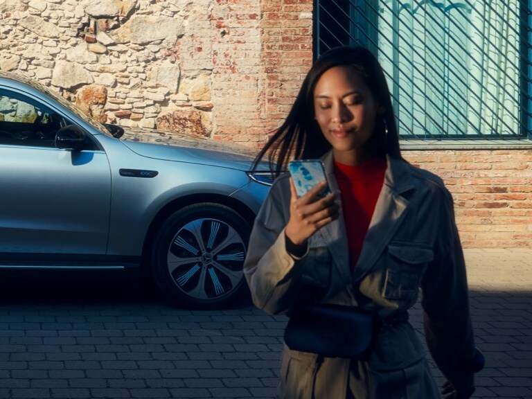 Kobieta korzysta z aplikacji Mercedes-Benz na swoim smartfonie.