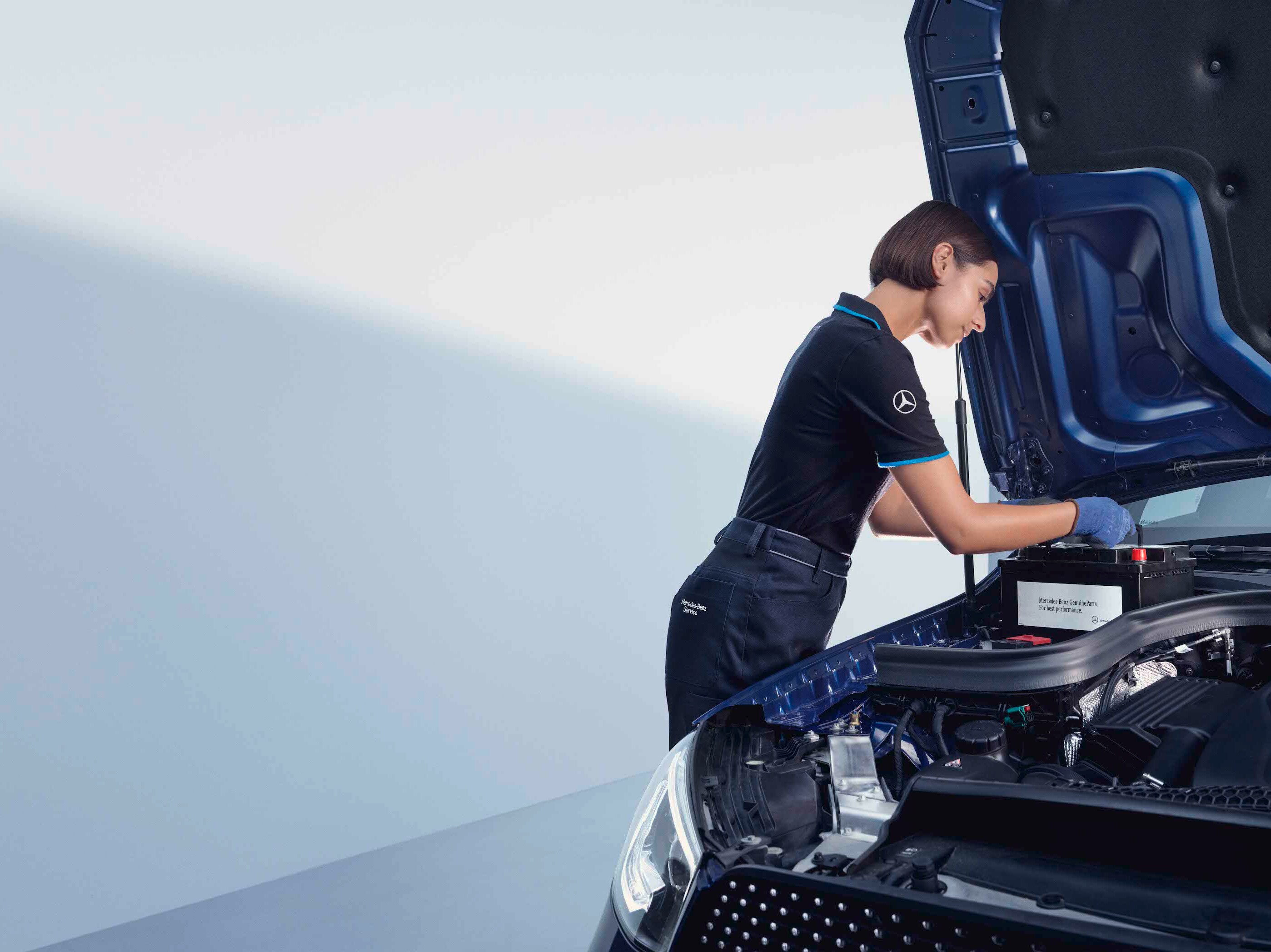 Mechanik samochodowy pochyla się nad otwartą maską samochodu Mercedes-Benz.