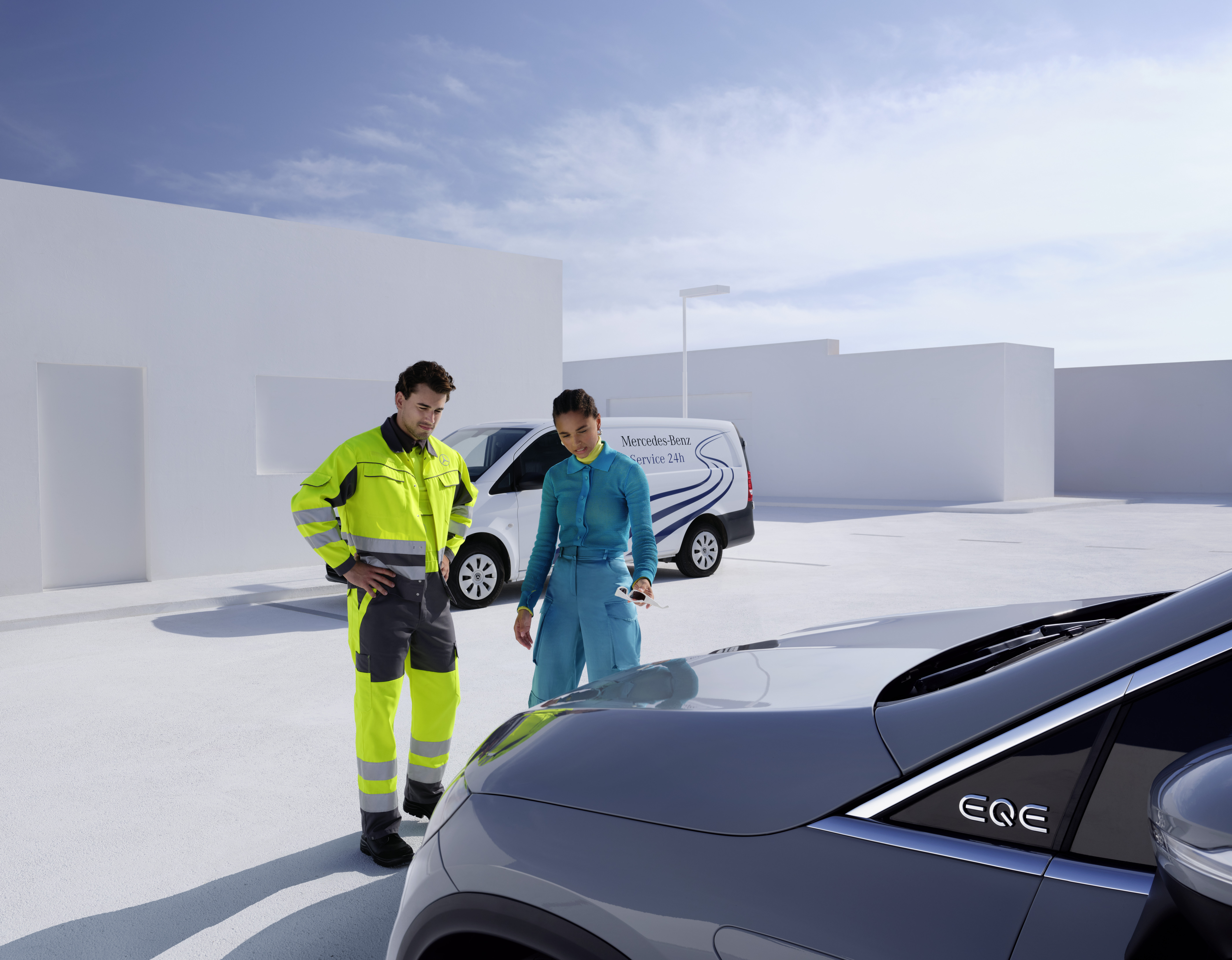 Pomoc drogowa | Mercedes-Benz Mężczyzna z zespołu serwisowego Mercedes-Benz i kobieta patrzą na samochód Mercedes-Benz