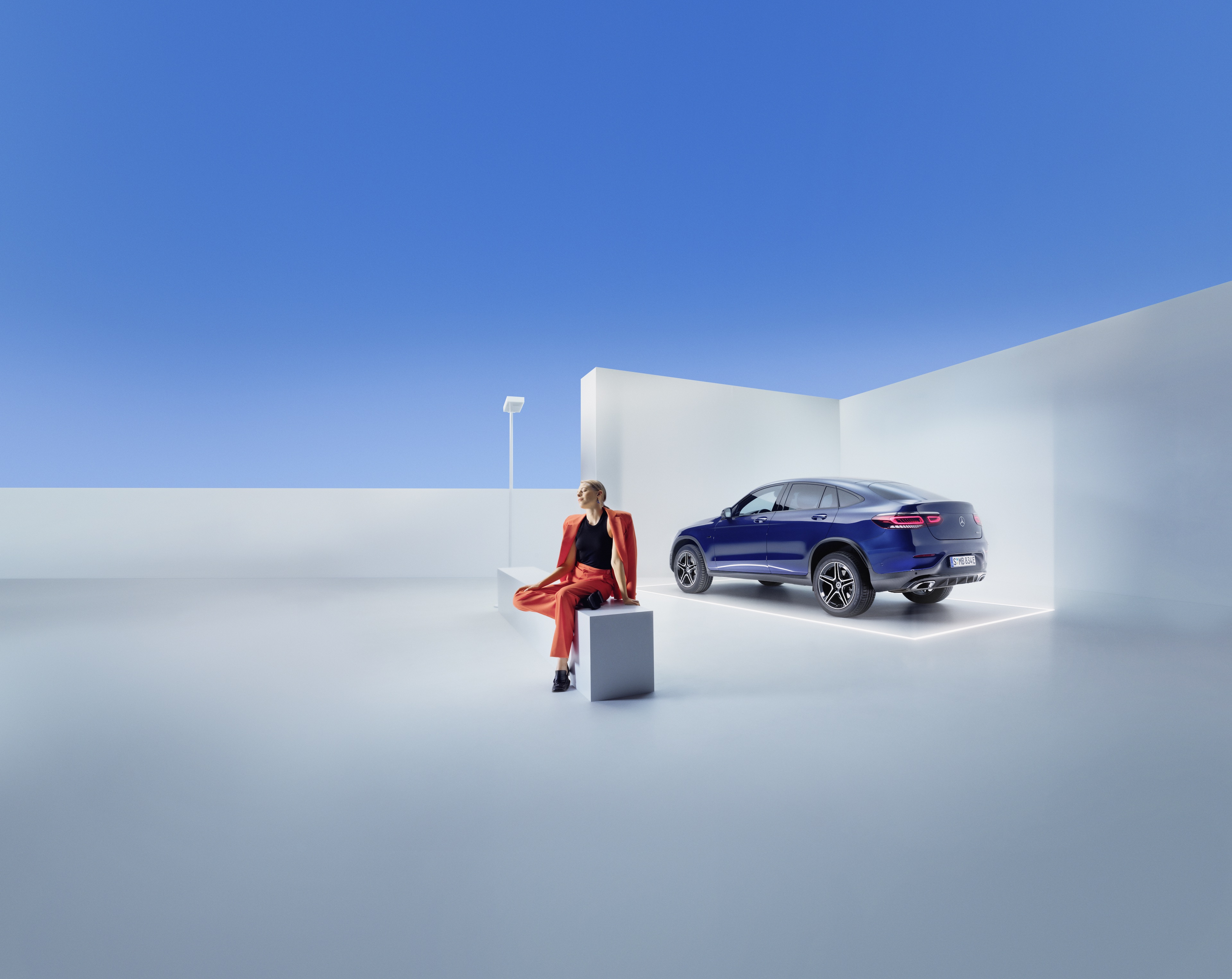 Pakiety serwisowe | Mercedes-Benz Kobieta siedzi na ławce przed swoim pojazdem marki Mercedes-Benz.
