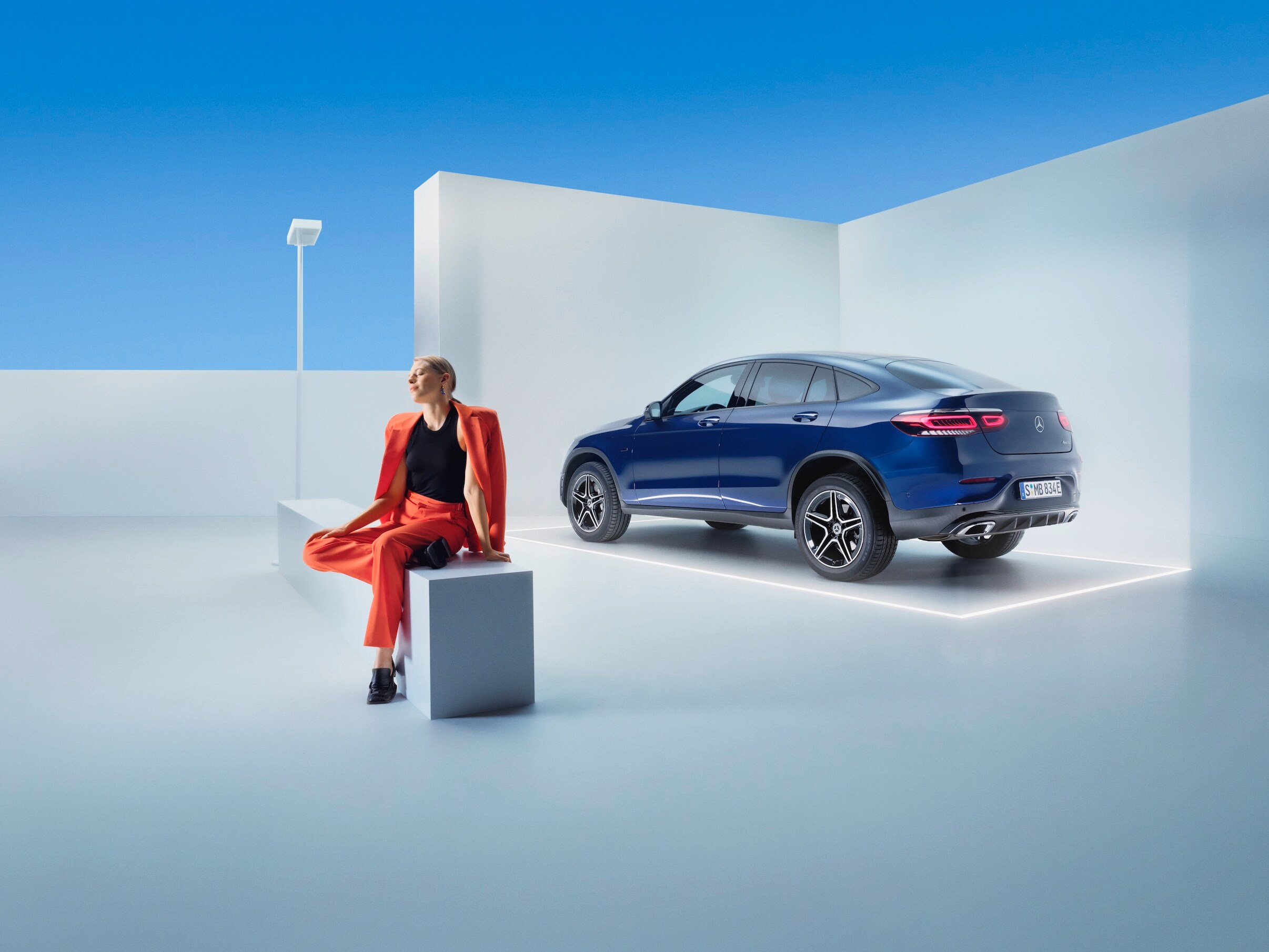 Kobieta relaksuje się na ławce przed swoim Mercedesem GLC.
