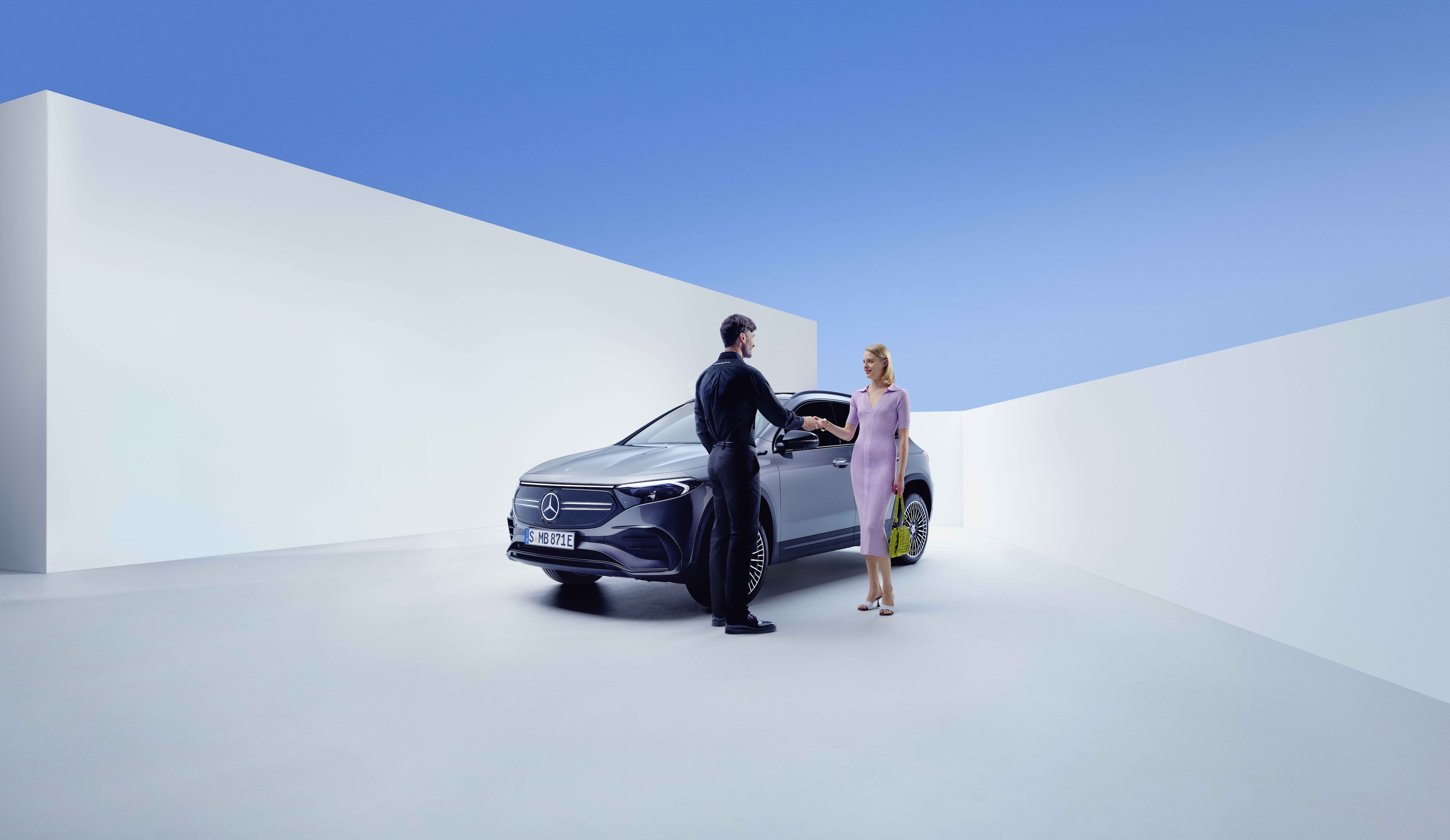 Serwis i naprawa | Mercedes-Benz Pracownik Mercedes-Benz i kobieta wymieniają uścisk dłoni przed Mercedesem EQA.