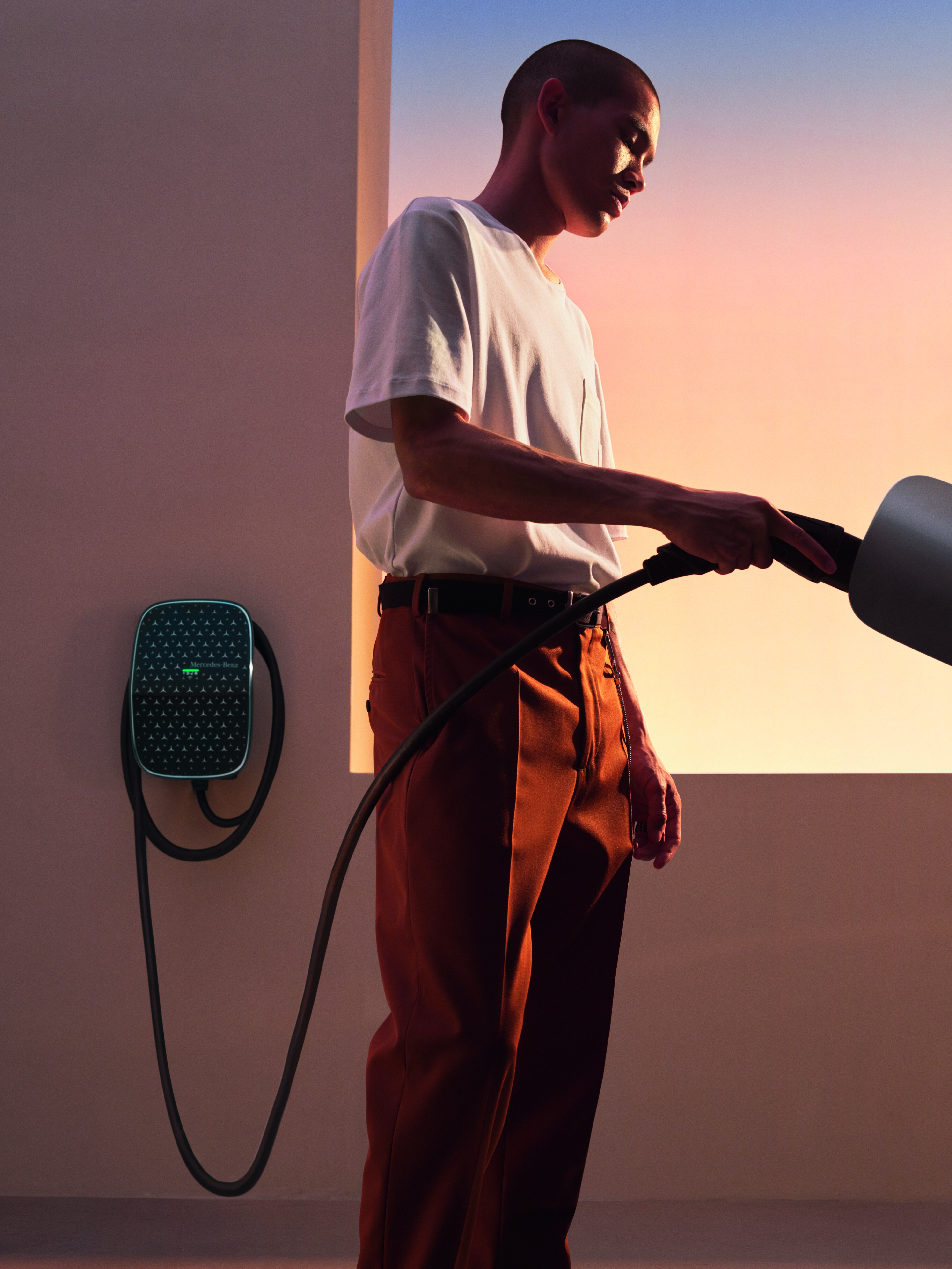 Kierowca podłącza Mercedesa EQA do stacji ładowania Mercedes-Benz Wallbox.