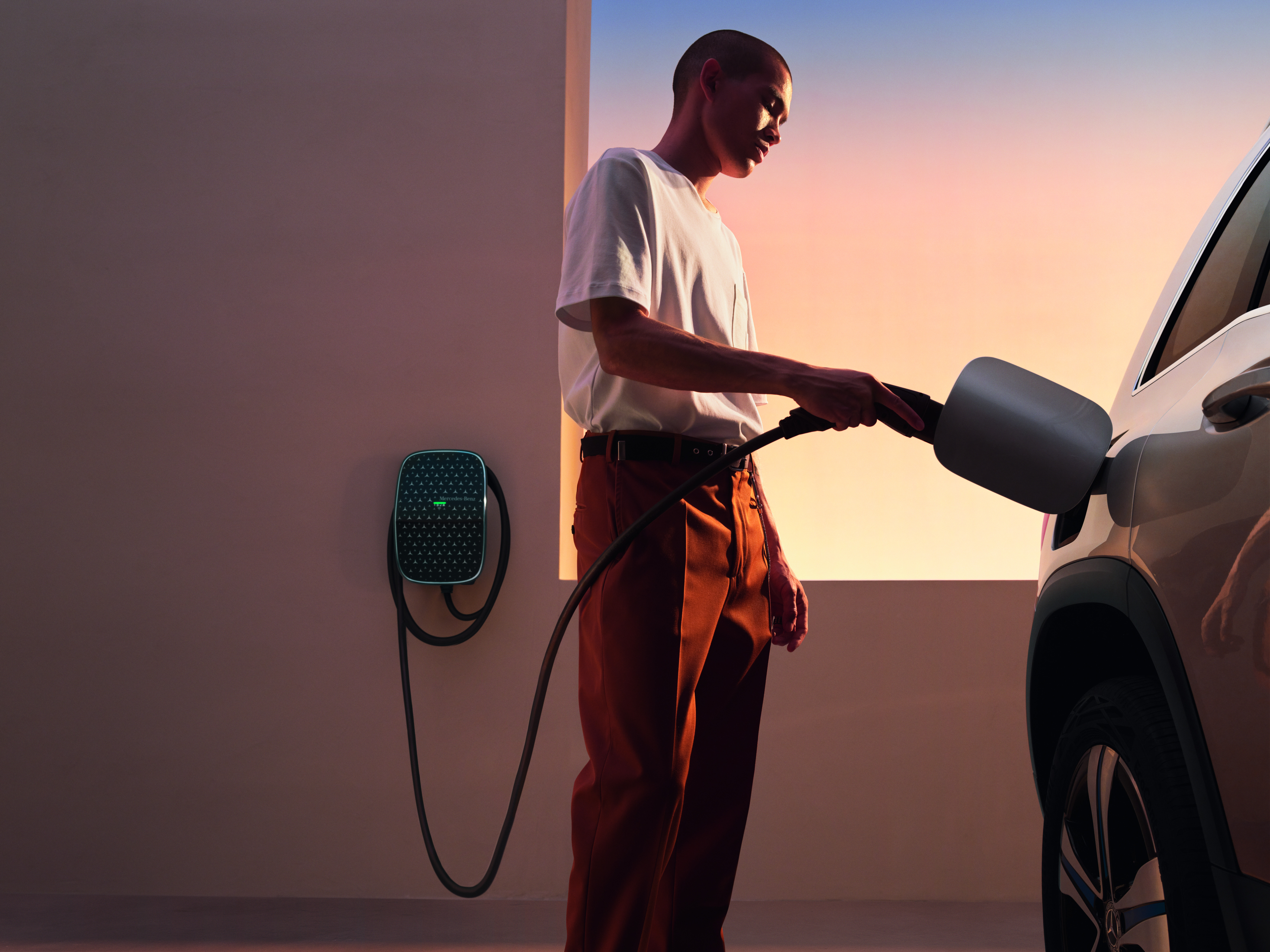 Partner instalacyjny stacji ładowania | Samochody elektryczne | Mercedes-Benz Kierowca podłącza Mercedesa EQA do stacji ładowania Mercedes-Benz Wallbox.