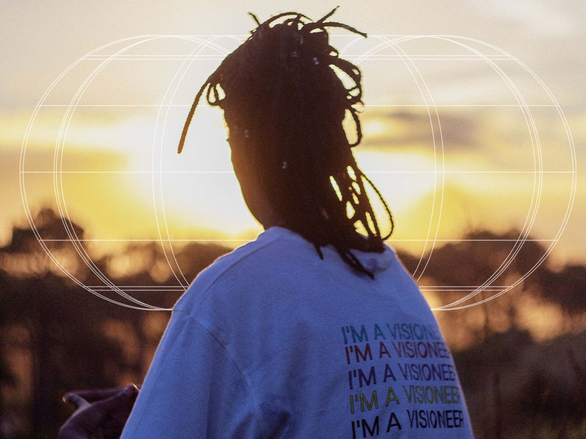 Widoczna od tyłu kobieta obserwująca zachód słońca w koszulce beVisioneers.