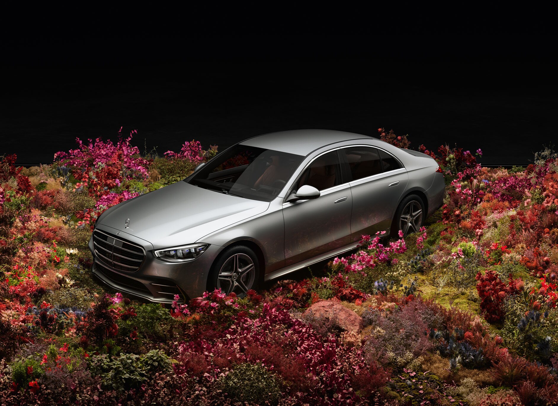 Srebrny Mercedes-Benz zaparkowany pośród kwiatów.