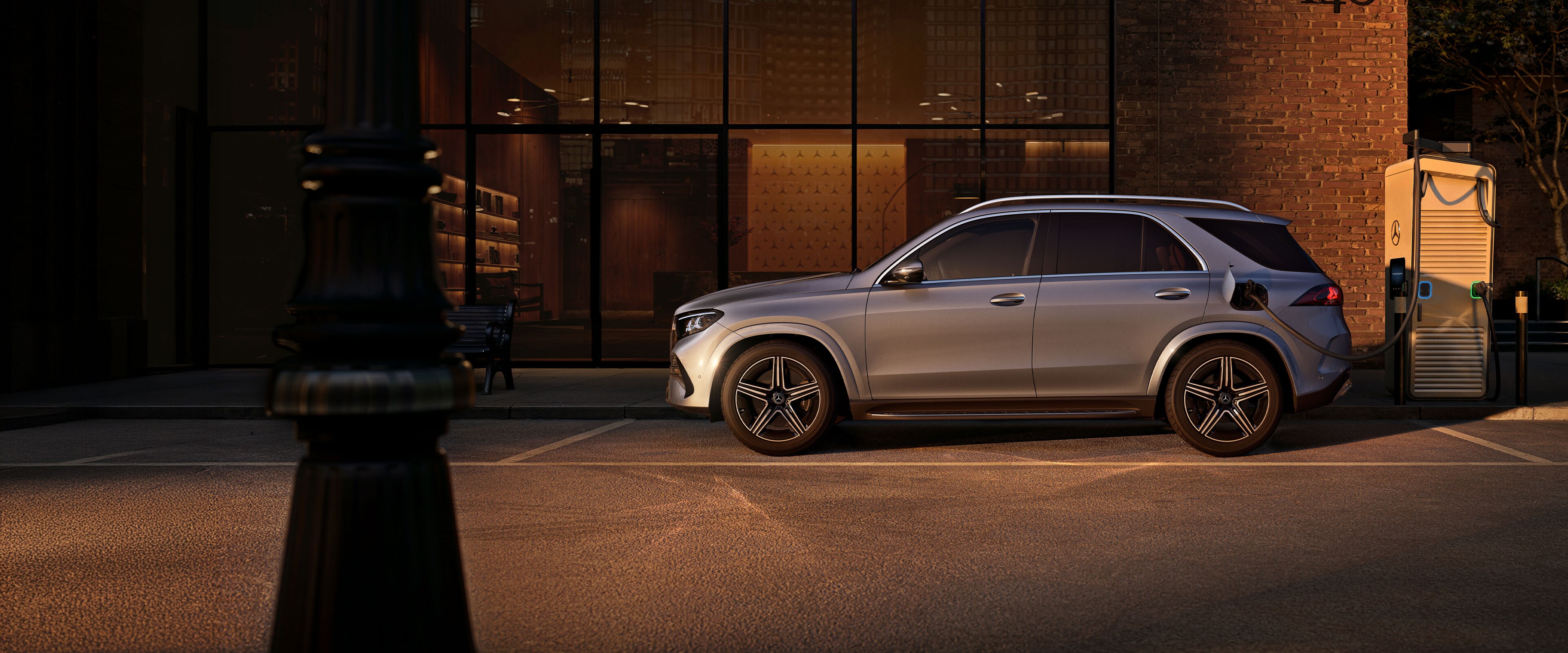 Samochód Mercedes-Benz z napędem hybrydowym plug-in, widziany z boku i od tyłu na stacji ładowania.
