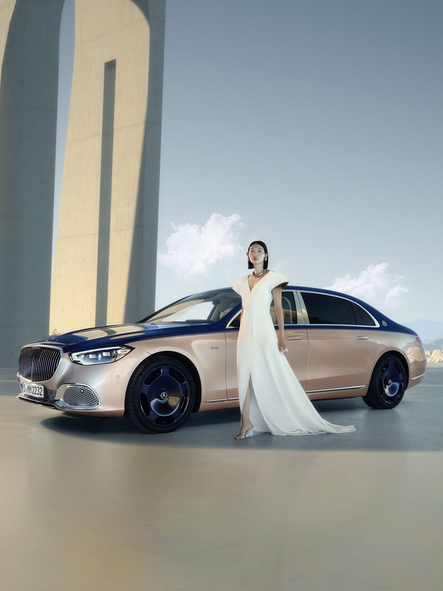 Kobieta w białej sukni stoi obok Klasy S Mercedes-Maybach.