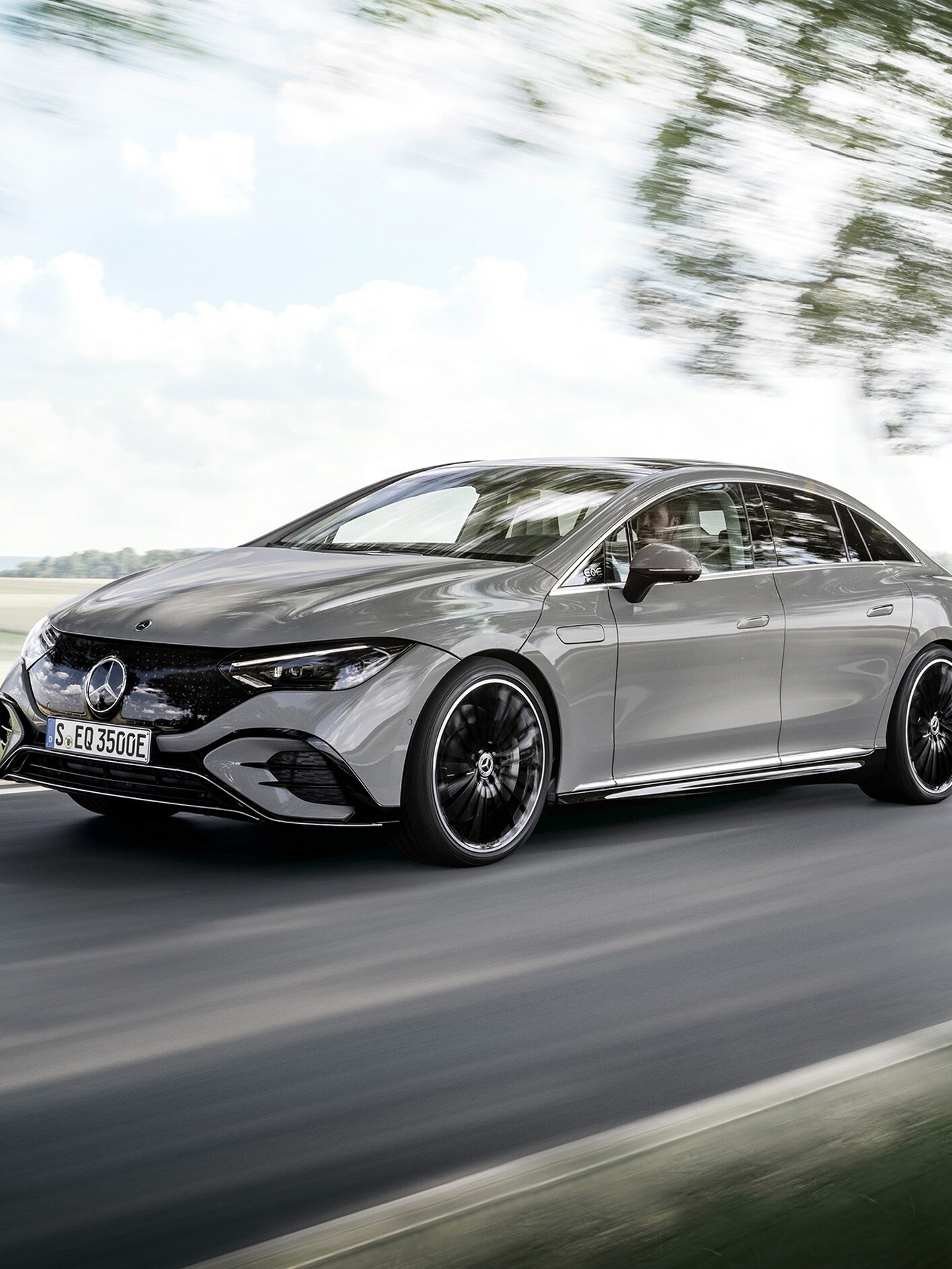 Mercedes-Benz EQS Limuzyna na drodze wśród drzew.