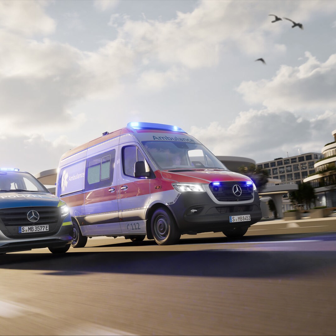 Dwa pojazdy specjalne Mercedes-Benz, karetka oparta na modelu Sprinter oraz pojazd policyjny z włączonymi niebieskimi światłami poruszają się w środowisku miejskim – to niezawodne rozwiązania dla służb ratowniczych i ratunkowych.