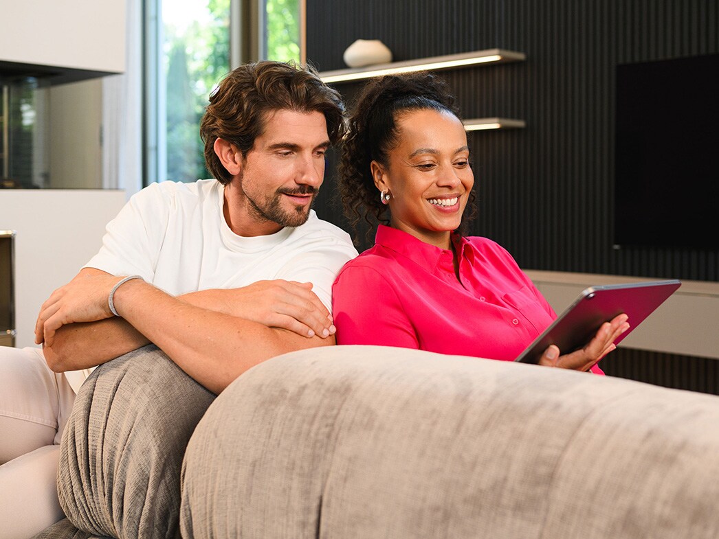 Dwie osoby patrzące na urządzenie mobilne.