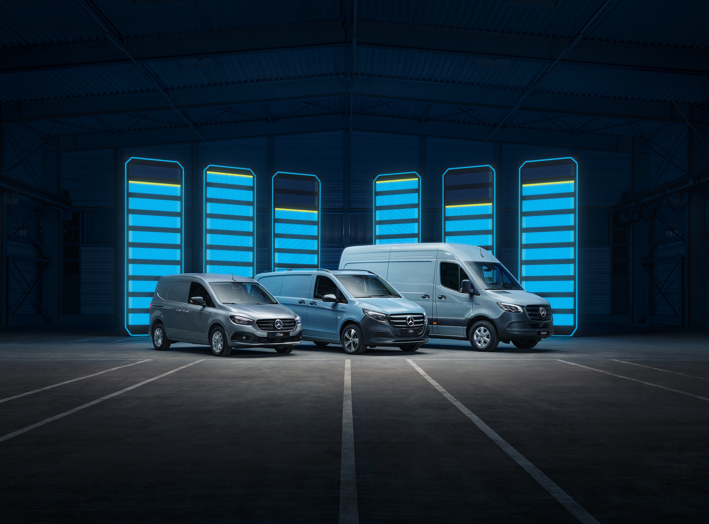 Elektryczne samochody dostawcze Mercedes-Benz | Historia pojazdów użytkowych | Mercedes-Benz Eektryczne samochody dostawcze Mercedes-Benz zaprezentowany w futurystycznym magazynie z podświetlonymi paskami ładowania