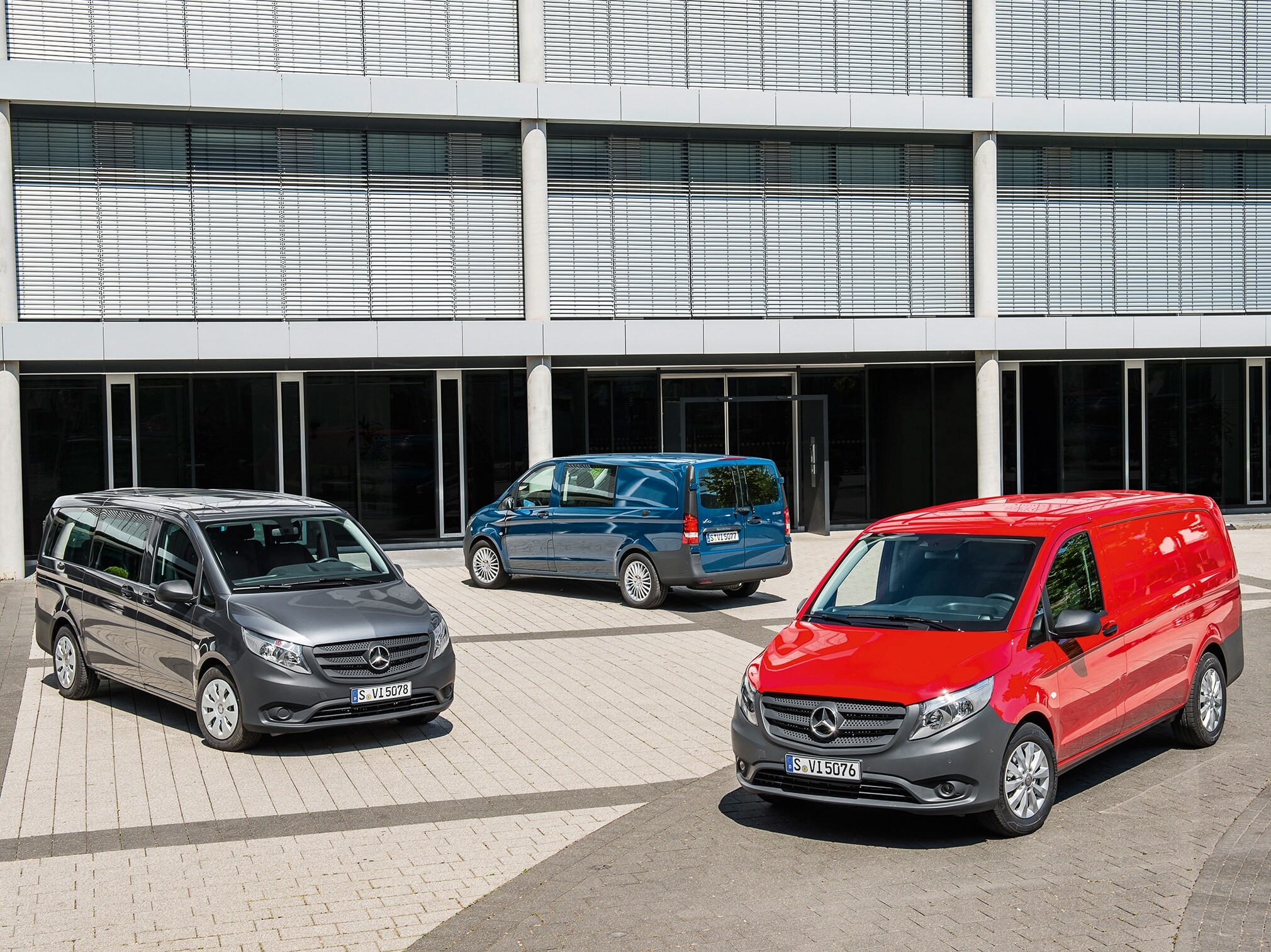 Kilka samochodów Mercedes-Benz Vito zaparkowanych przed nowoczesnym budynkiem biurowym