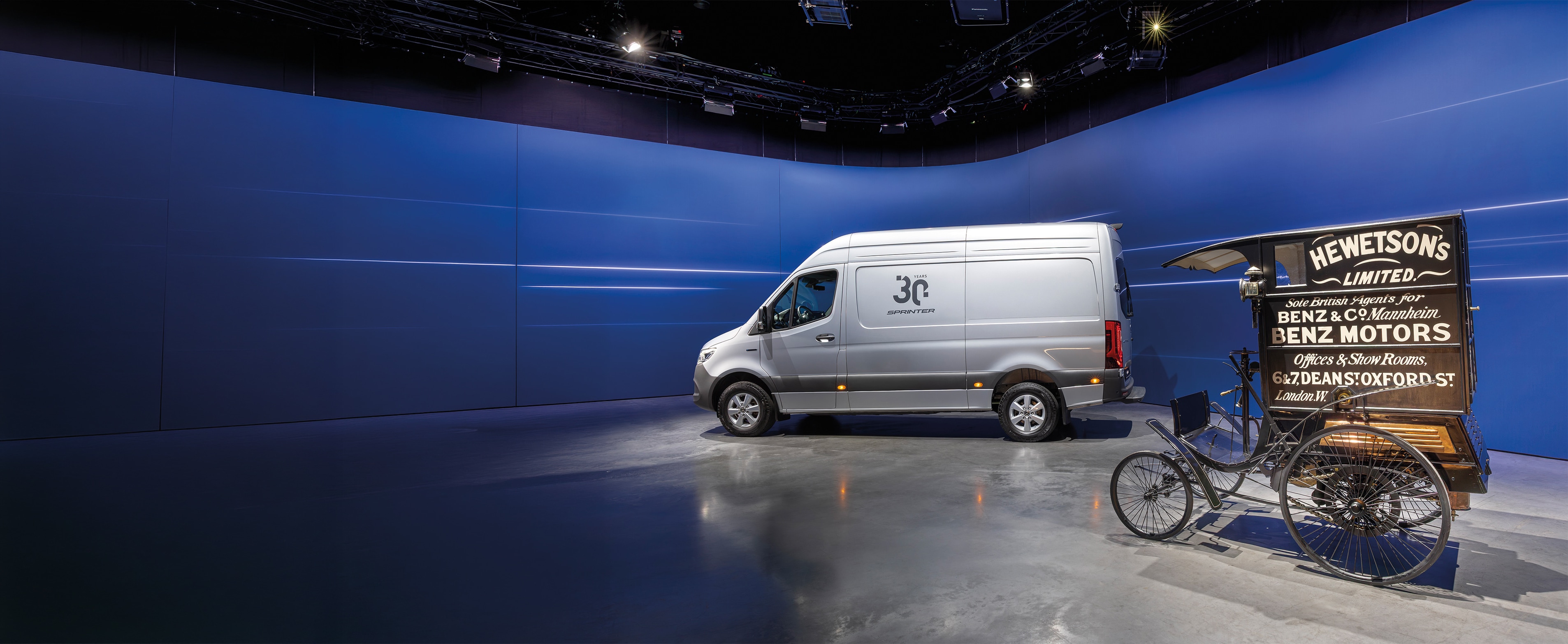 Historia | Pojazdy użytkowe | Mercedes-Benz Samochód dostawczy Mercedes-Benz Sprinter i zabytkowy samochód dostawczy marki Benz wystawione w nowoczesnym salonie