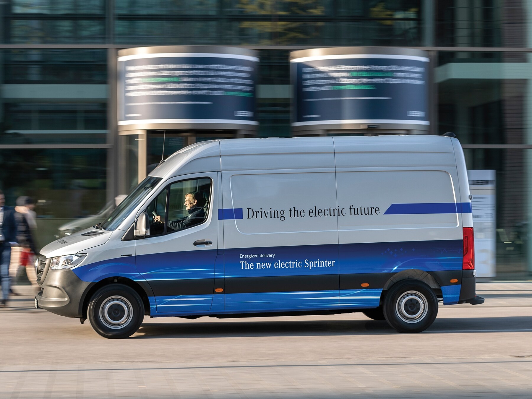 Mercedes-Benz eSprinter ze skrzynią ładunkową jadący nowoczesną ulicą miasta
