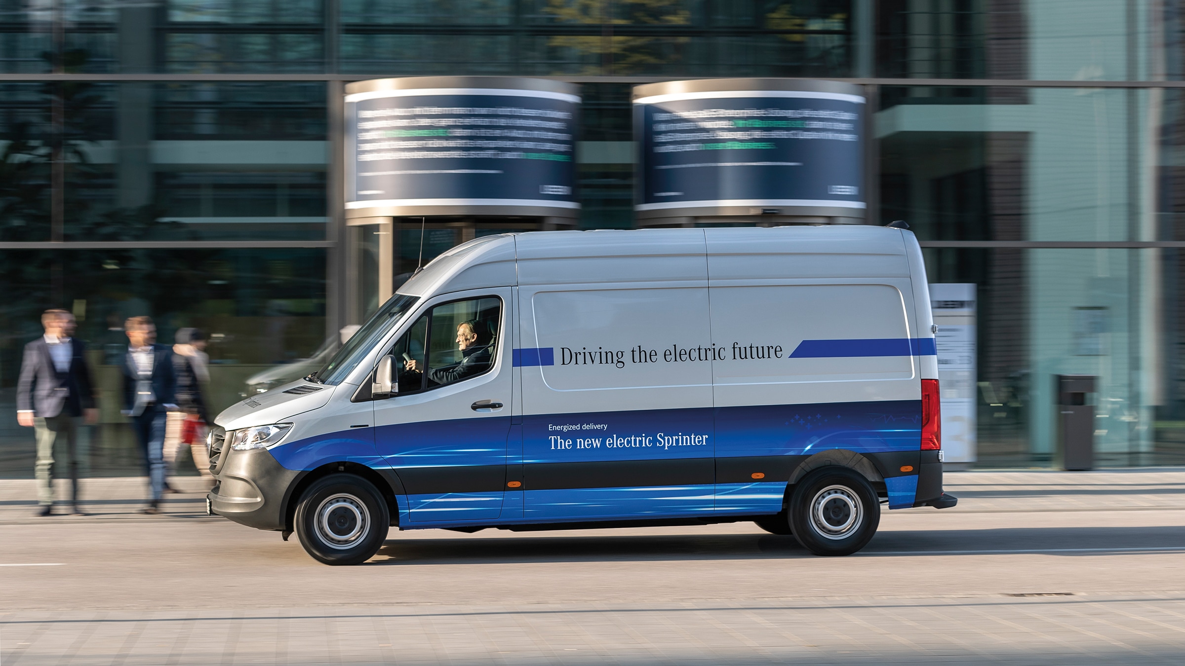 eSprinter drugiej generacji ze skrzynią ładunkową | Historia pojazdów użytkowych | Mercedes-Benz Mercedes-Benz eSprinter ze skrzynią ładunkową jadący nowoczesną ulicą miasta