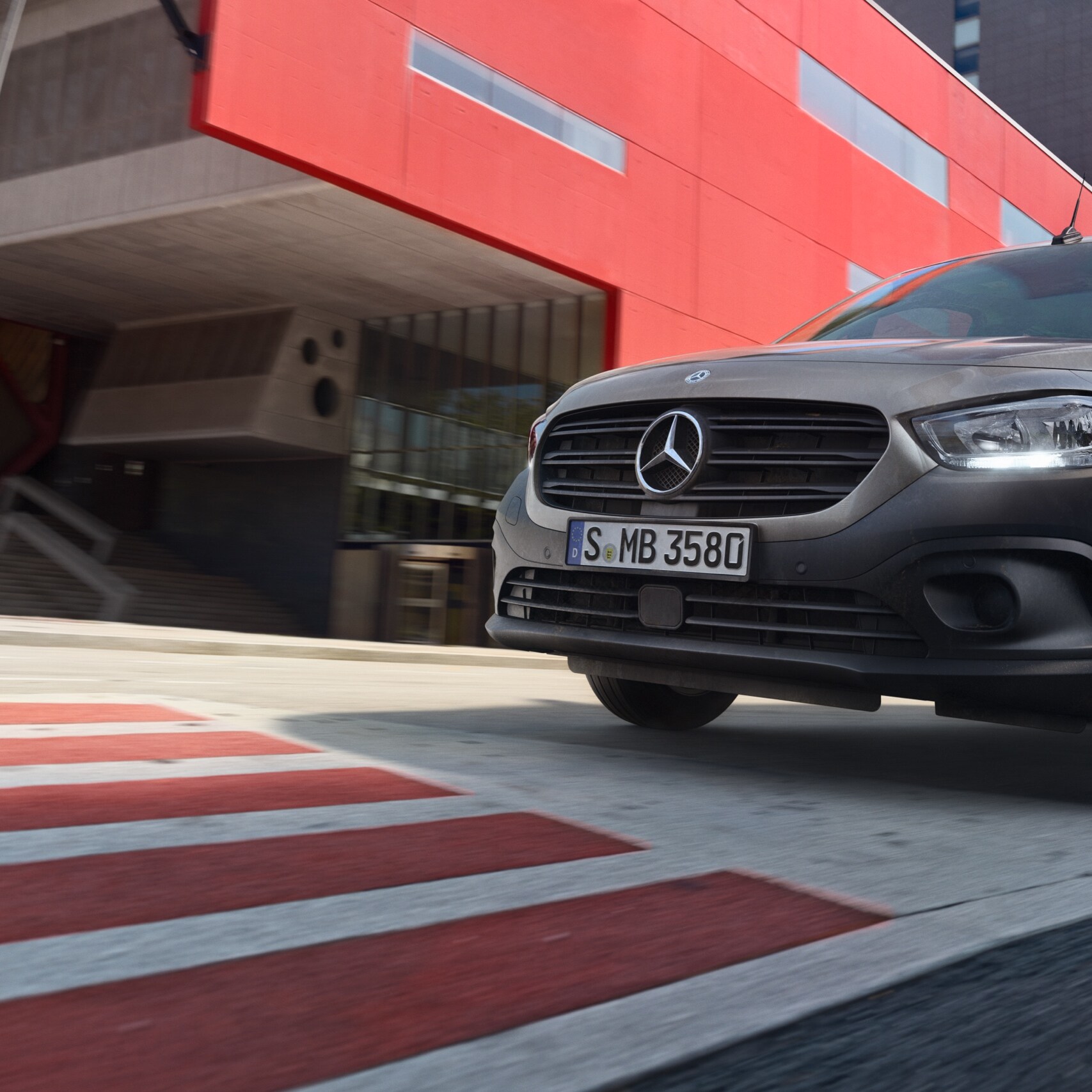 Citan Tourer, kompaktowy samochód dostawczy od Mercedes-Benz, jedzie przez nowoczesną aglomerację miejską.