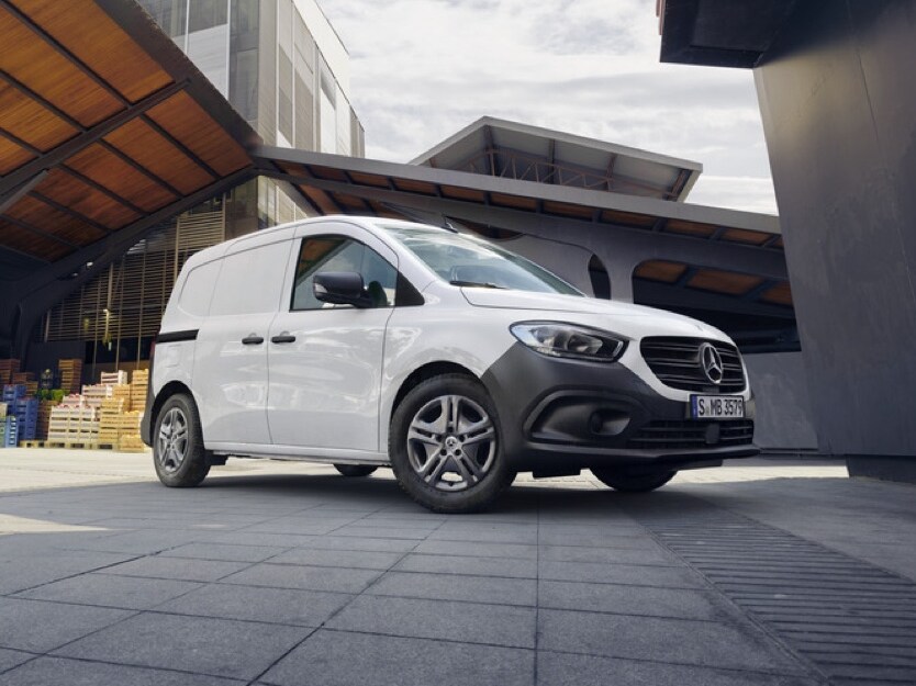 Biały Mercedes-Benz Citan na tle industrialnego krajobrazu.