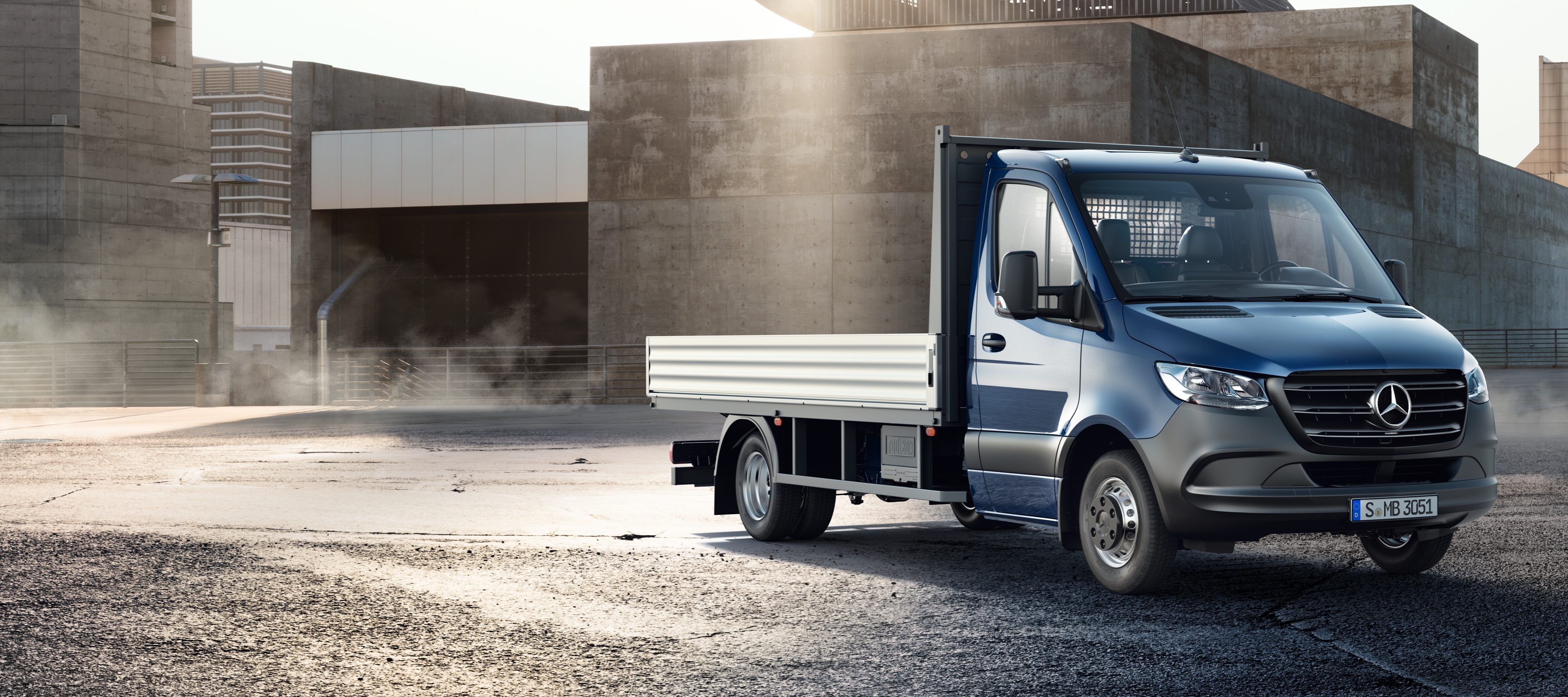 Dane techniczne Sprintera Podwozia ze skrzynią ładunkową | Samochody dostawcze Mercedes-Benz Granatowy Sprinter Podwozie ze skrzynią ładunkową na tle budynków przemysłowych.