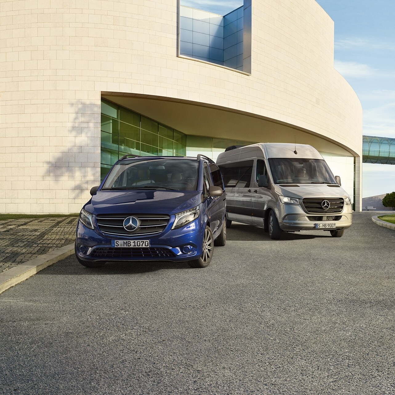 Mercedes-Benz Vito Tourer i Sprinter Tourer stojące przed nowoczesnym domem.