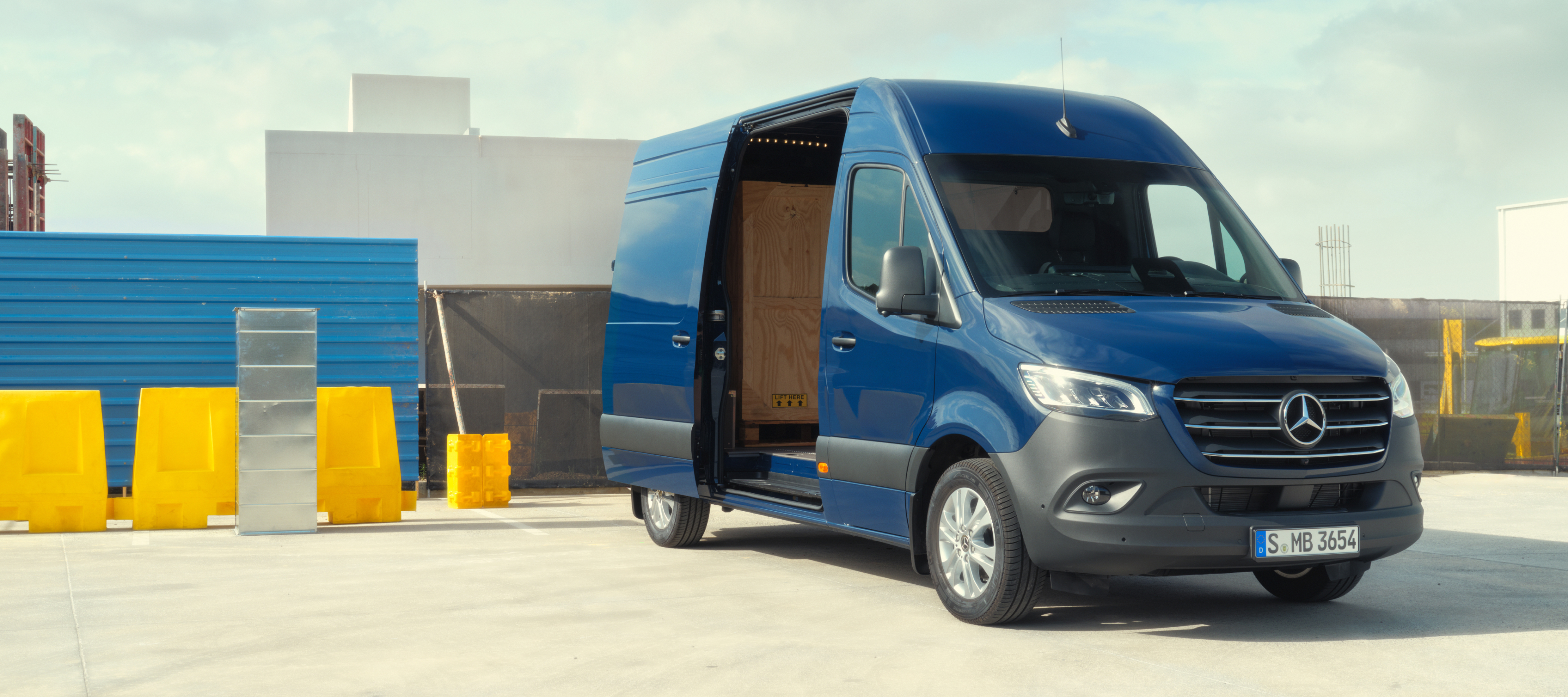Porównanie pojazdów | Sprinter Furgon | Mercedes-Benz Mercedes-Benz Sprinter Furgon stojący przed materiałami budowlanymi.