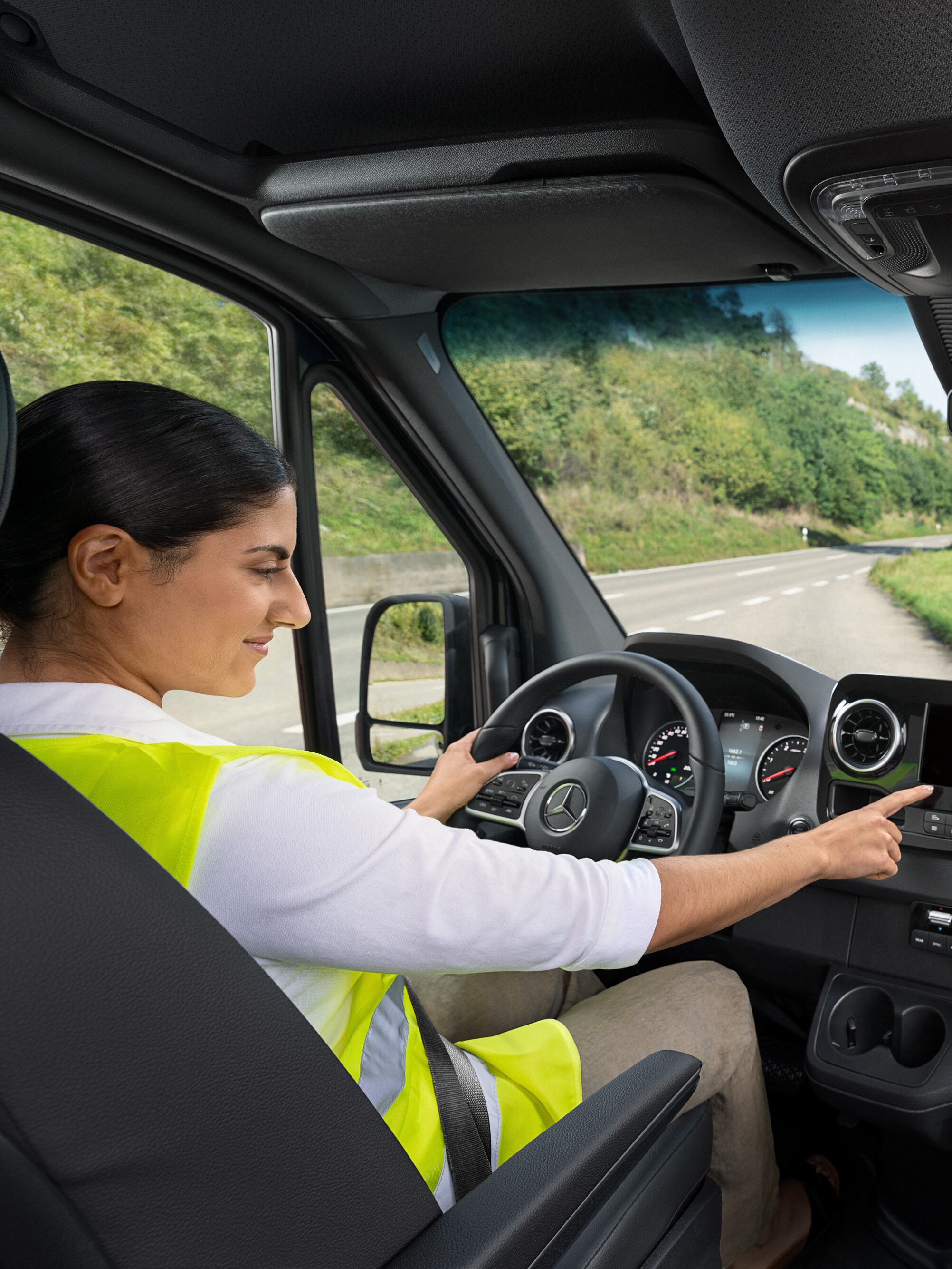 Kierowca w samochodzie Mercedes-Benz Sprinter dzwoni na infolinię Service24h Mercedes-Benz za pośrednictwem menu pokładowego.