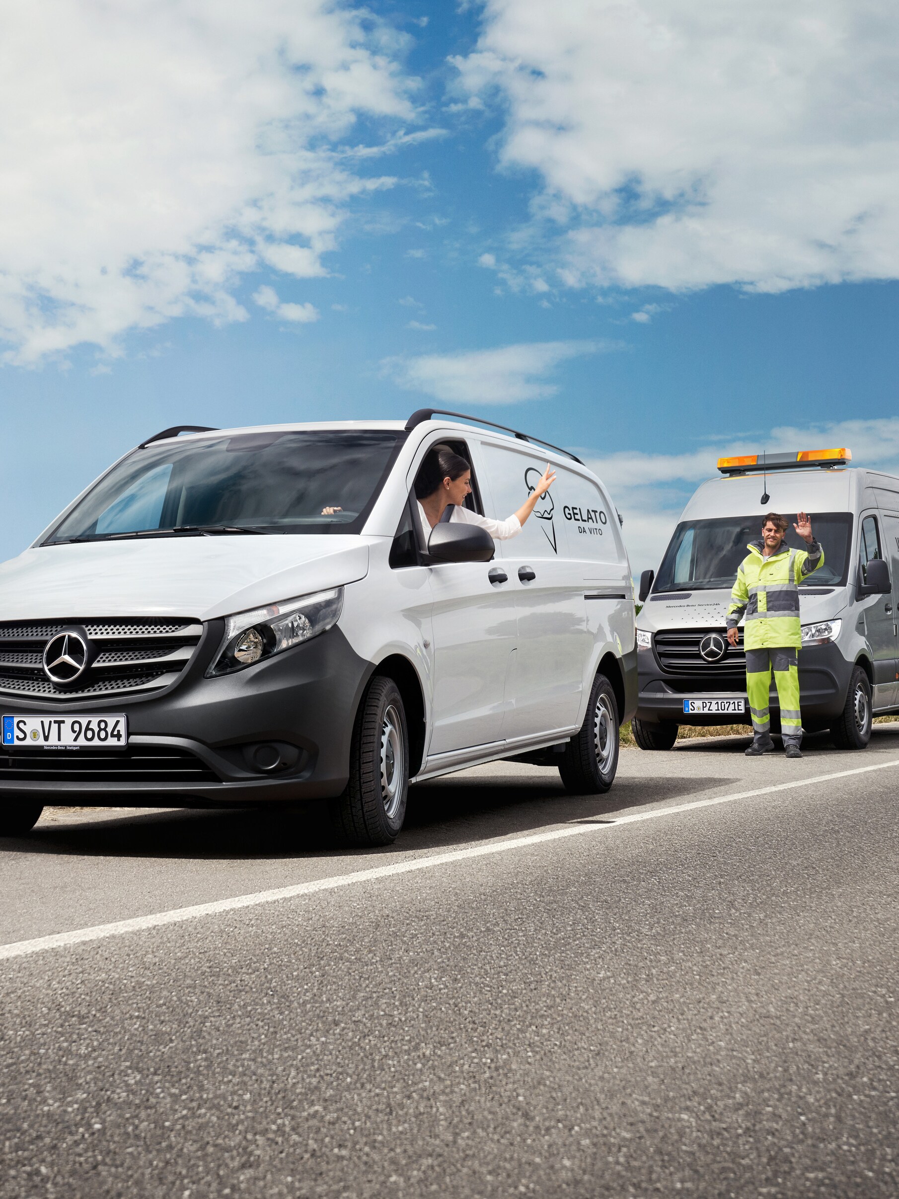 Kobieta siedząca w białym samochodzie Mercedes-Benz Vito macha do doradcy serwisowego Mercedes-Benz na poboczu drogi.